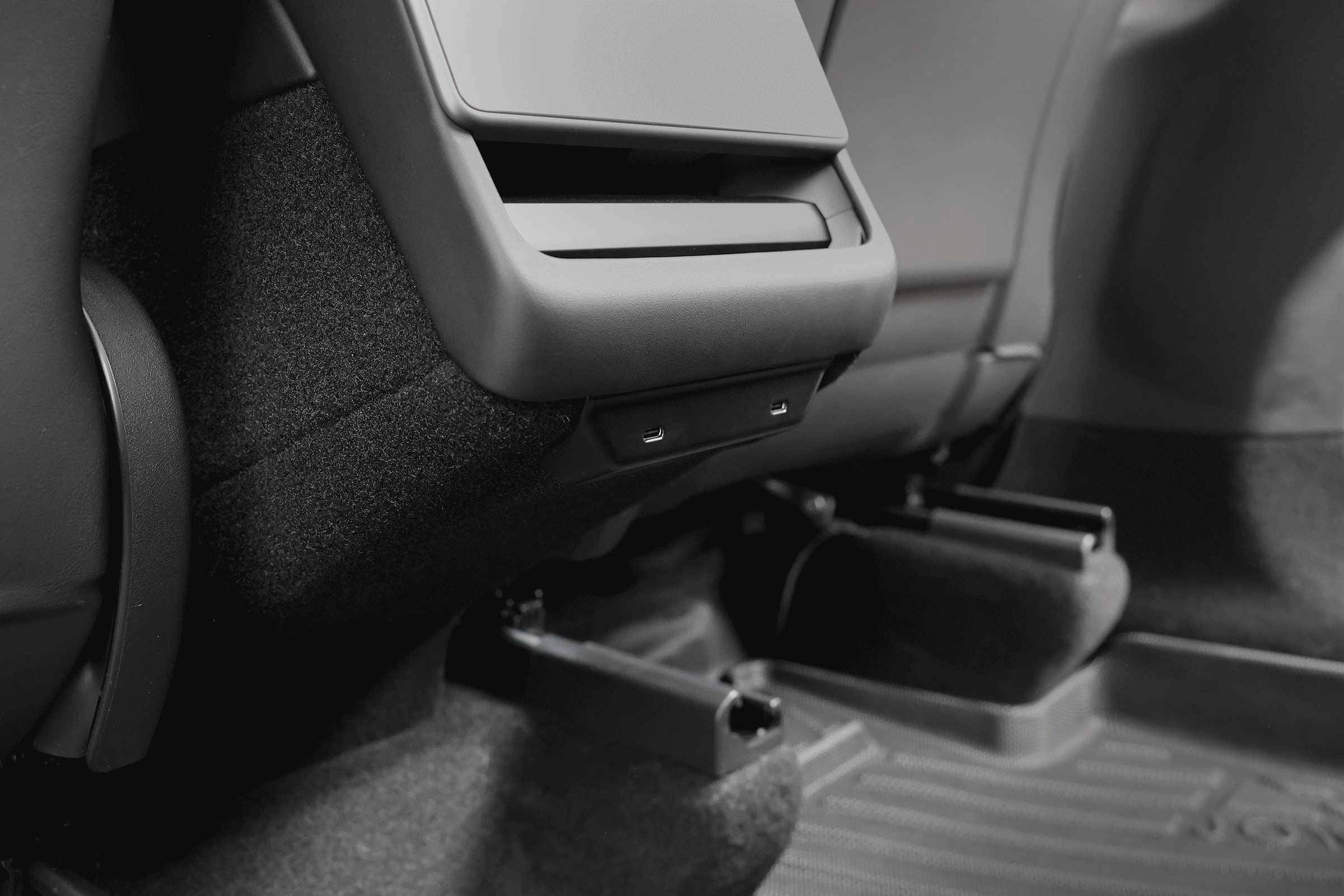 Close-up of a JOWUA 130W LED Rear Vent Hub (Model 3 Highland 2024+/Model Y Juniper 2025+) with USB-C fast charging under the rear air vent, along with textured floor mats and visible seat rails.