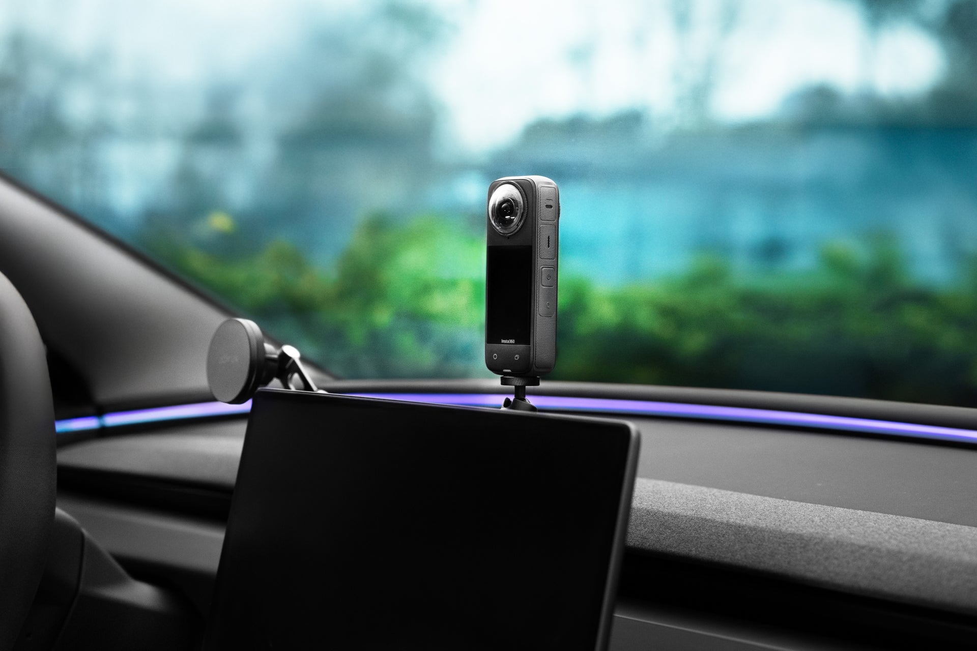 A JOWUA 360° Multi Function Mount with a 360-degree camera is installed on a car dashboard behind the display screen, with greenery visible in the blurred background outside the window.