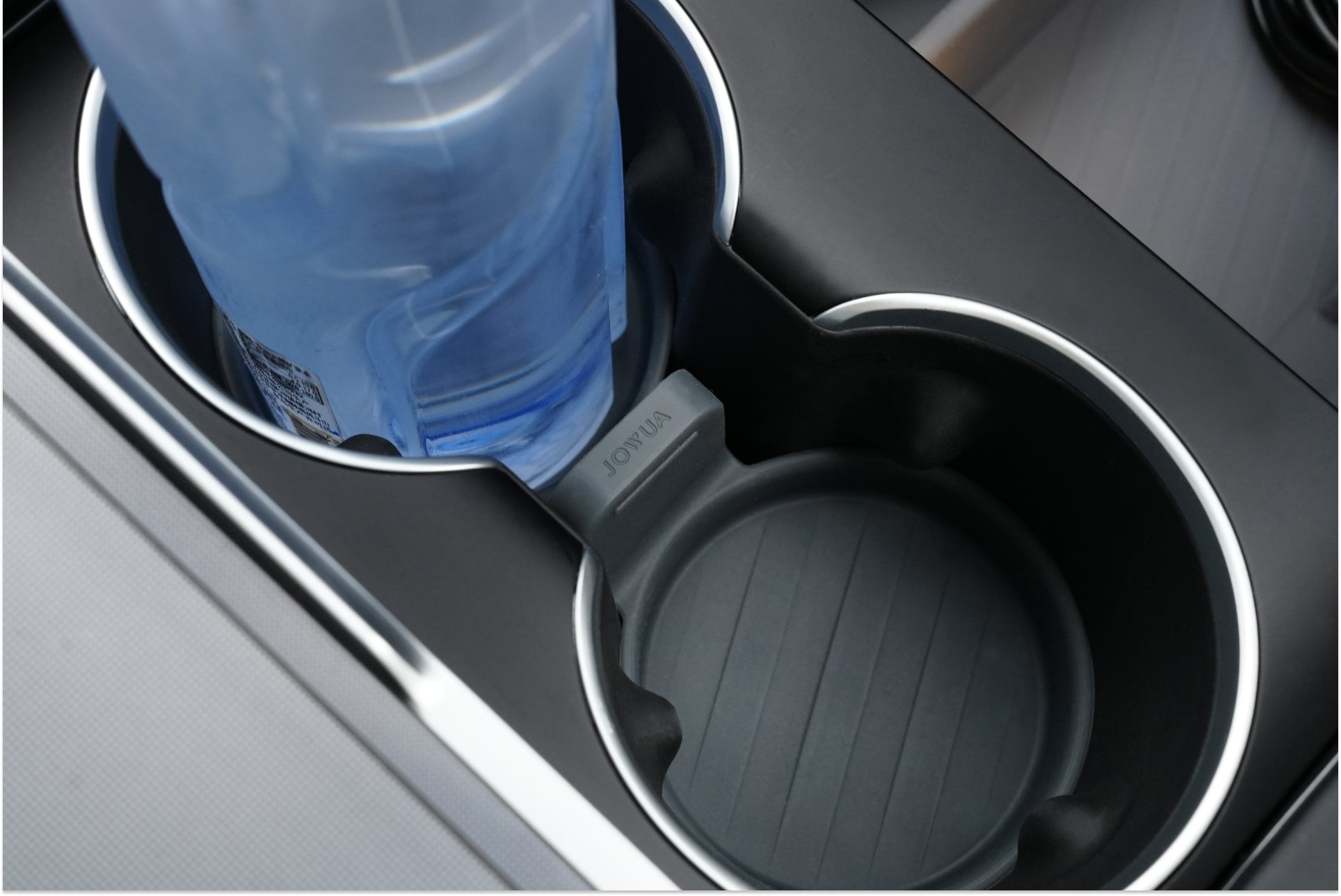 A water bottle sits in the left cup holder of JOWUA's LED Center Console Combo, a stylish addition to the Tesla Reengineered Model 3 Highland (2024+), featuring a sleek black design. The premium silicone comes equipped with a divider marked "REMOVE," while the right cup holder remains open, ready for use.