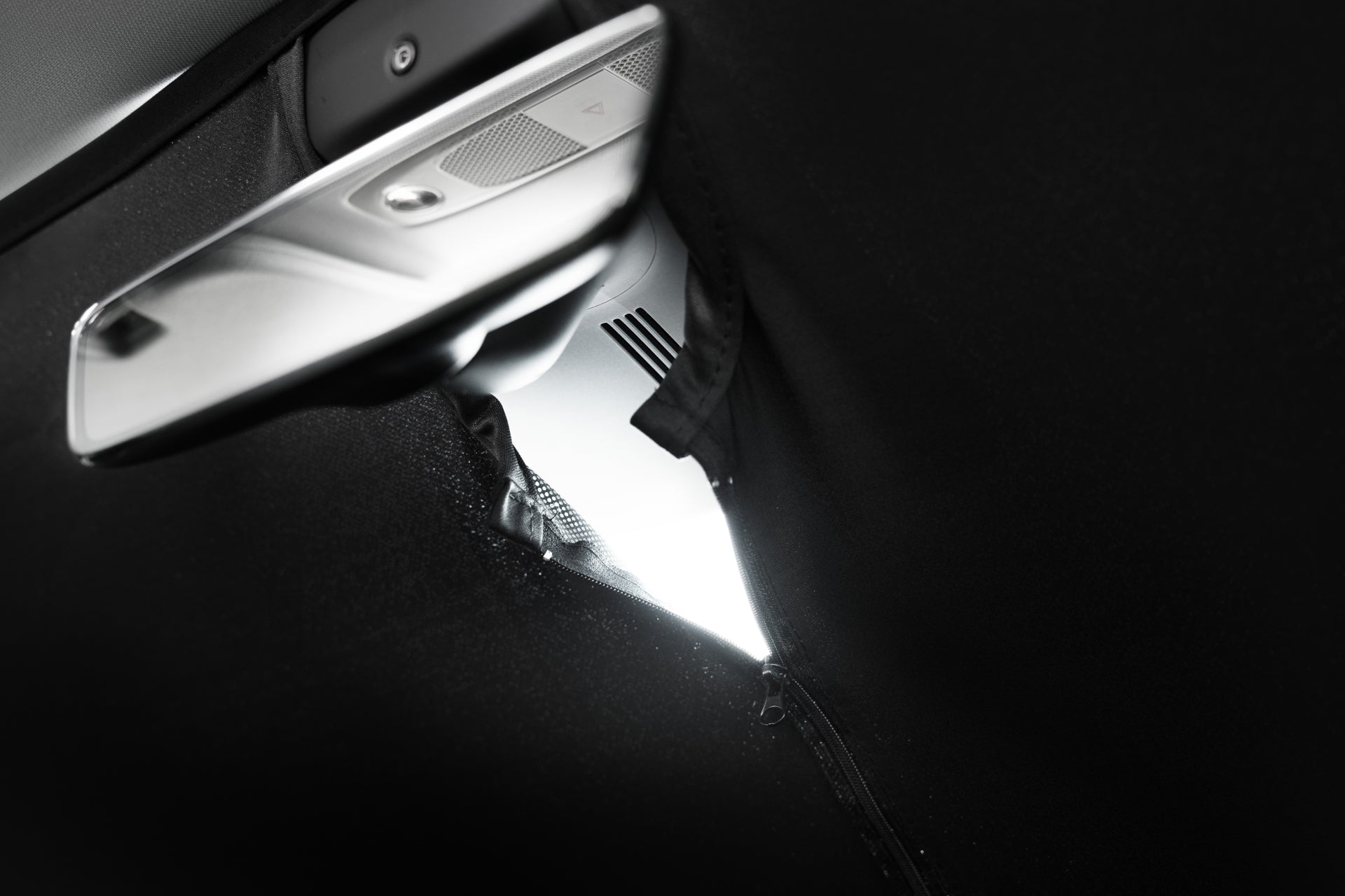 A close-up shows a JOWUA Windshield Sunshade for Model Y 2021-2024 partially covering a car’s side mirror, with a small opening letting in light. The car’s window and an interior speaker are also partially visible.