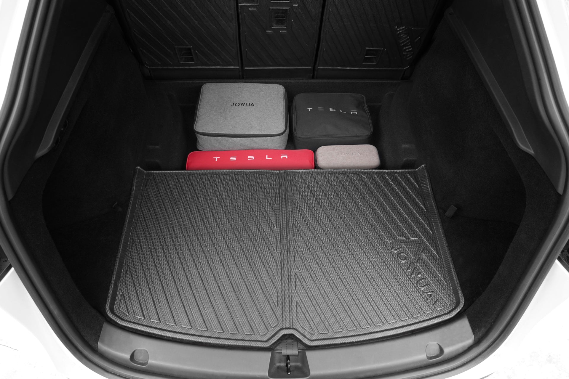 The trunk of a Tesla Model Y (Juniper 2025+) is organized with JOWUA-labeled storage cases, all neatly arranged on the EasyShield Waterproof Trunk Liner + Rear Seats Back Cover Bundle by JOWUA, made from durable TPE material.