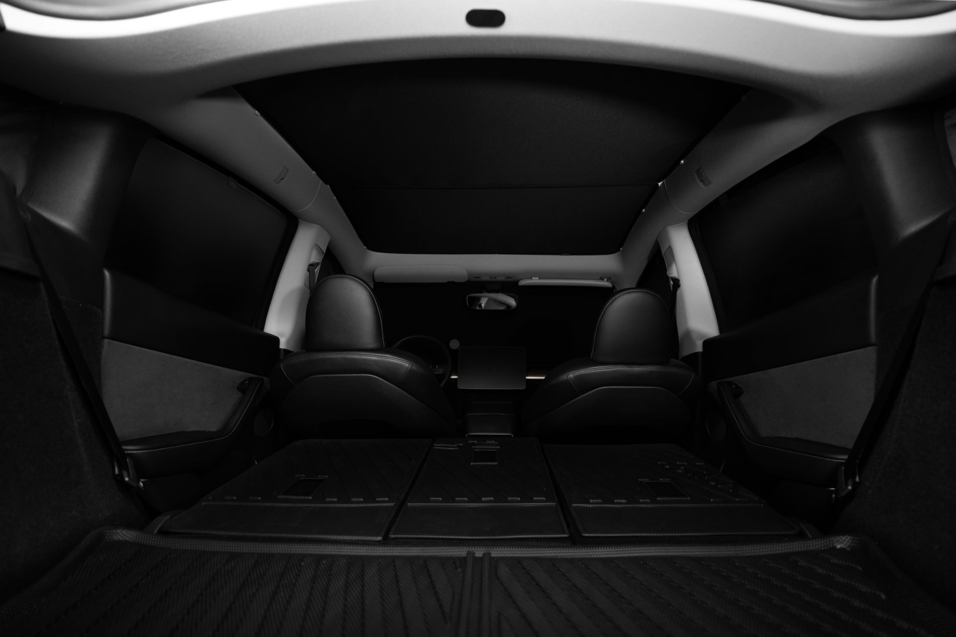 A photo from the rear of a vehicle displays the backseat and trunk area, where the seats are folded down to maximize cargo space. The image emphasizes a spacious and modern interior, showcasing Dark Matter mesh fabric upholstery that enhances its stylish look.