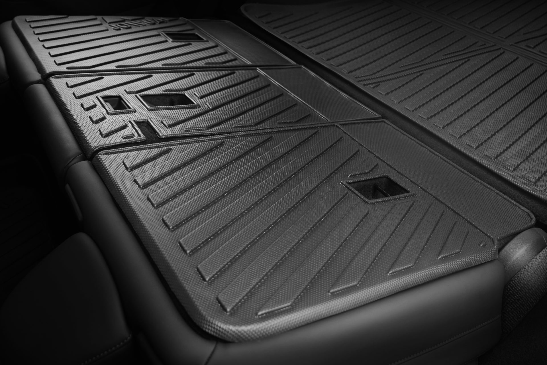 Close-up of the rear area of a Tesla Model Y (Juniper 2025+) with folded seats, protected by the JOWUA EasyShield Waterproof Trunk Liner + Rear Seats Back Cover Bundle, featuring durable TPE material with geometric patterns and rectangular cutouts.