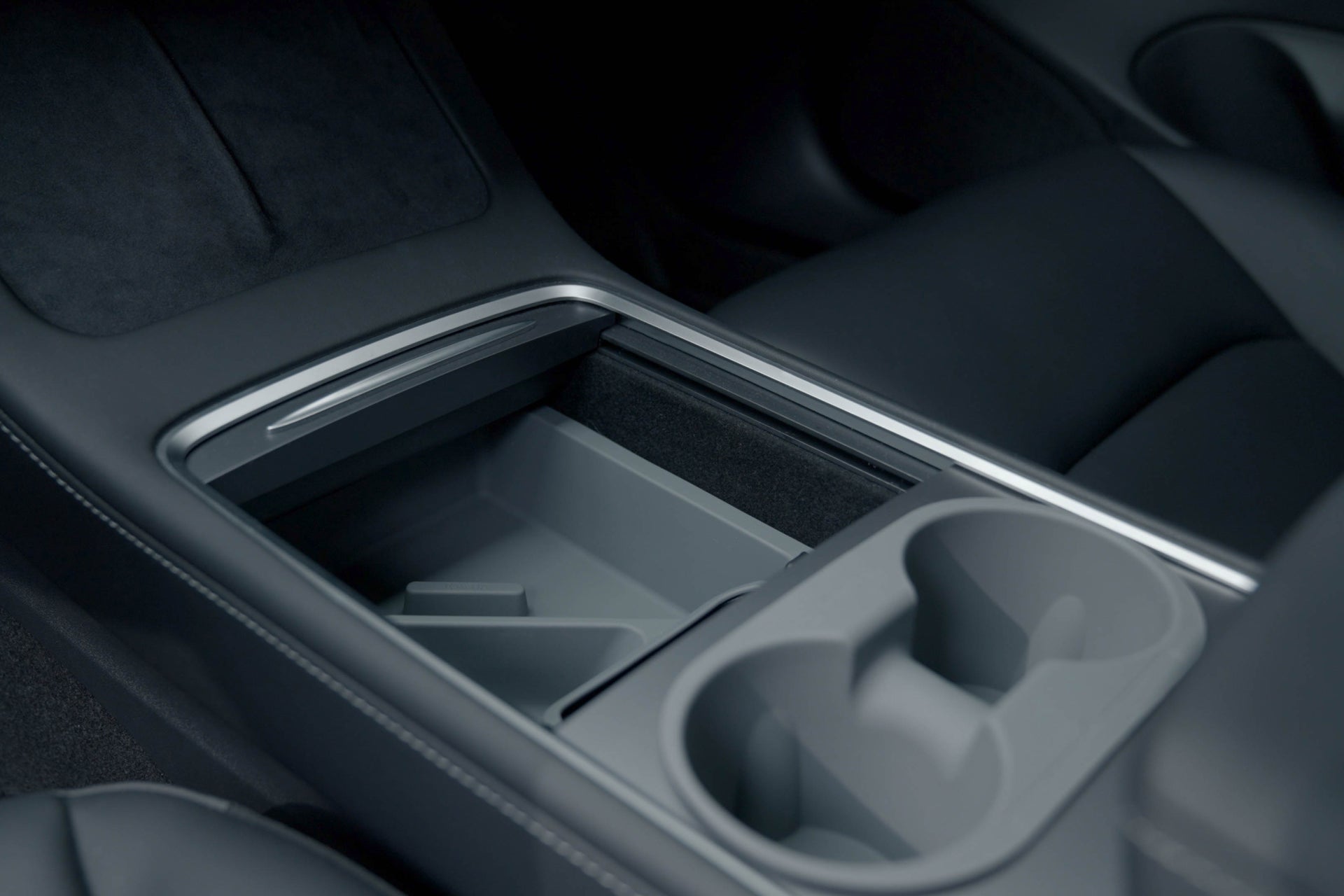 Close-up of the interior of a Tesla Model Y with the JOWUA LED Center Console Combo, showcasing a sleek organizer equipped with two cup holders and an empty storage compartment, enhanced by elegant gray and black materials.