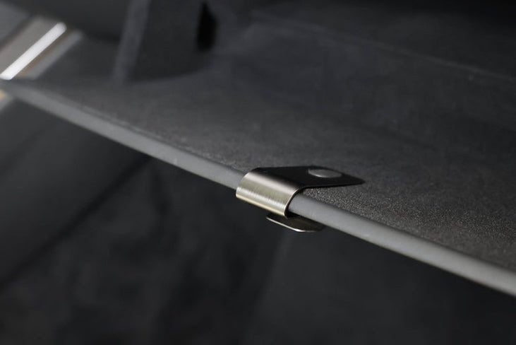 Close-up of a metal clip attached to a dark surface, likely from the JOWUA Premium Interior Essentials Set for Model Y Juniper (2025+); the background is blurred.