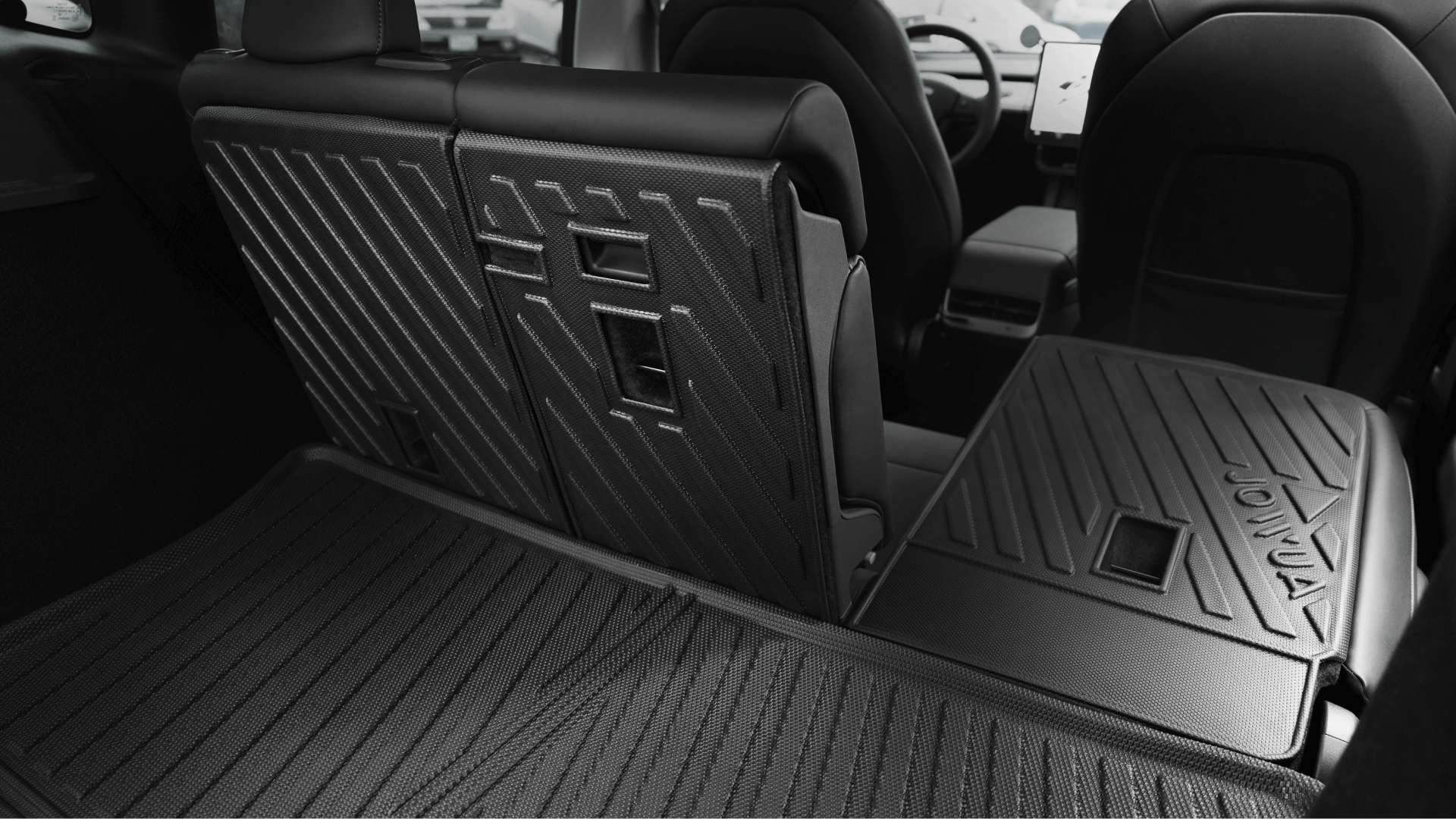 View of the Model Y trunk (2018-2024) with one rear seat folded and textured black backs visible, showcasing a spacious cargo area—perfect for installing the JOWUA Model Y Trunk Combo or other accessories.