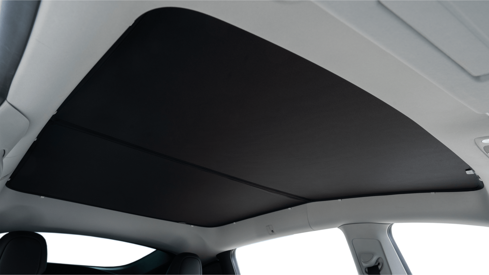 Interior view of a Model Y (Juniper 2025+) with the JOWUA Glass Roof Sunshade in black, offering UV protection over the panoramic glass roof; white trim and parts of seat headrests are also visible.