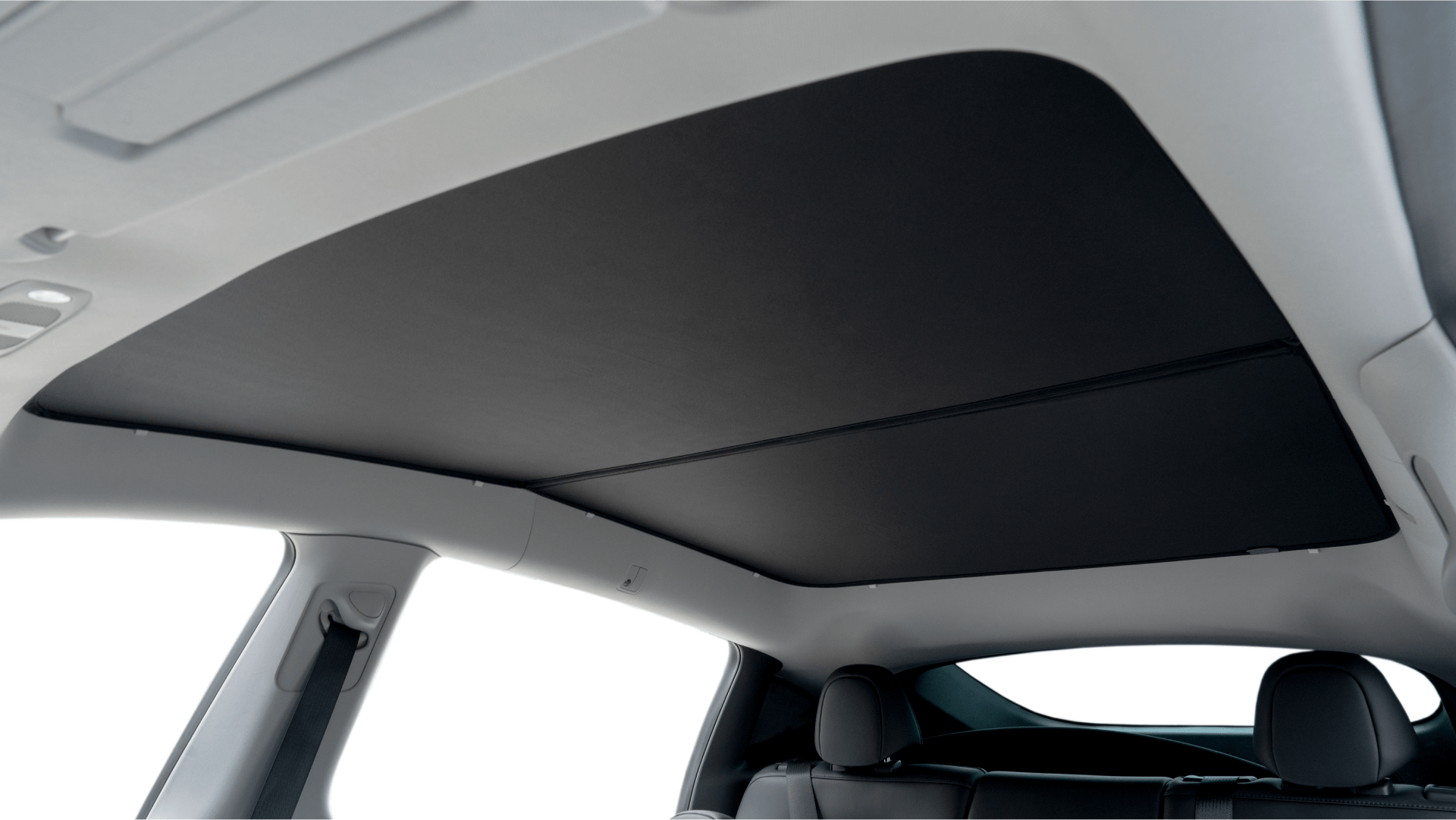 Interior view of a car with the JOWUA Model Y (Juniper 2025+) Glass Roof Sunshade closed for UV protection over the panoramic glass roof, showing two rear seats plus part of the door and window.