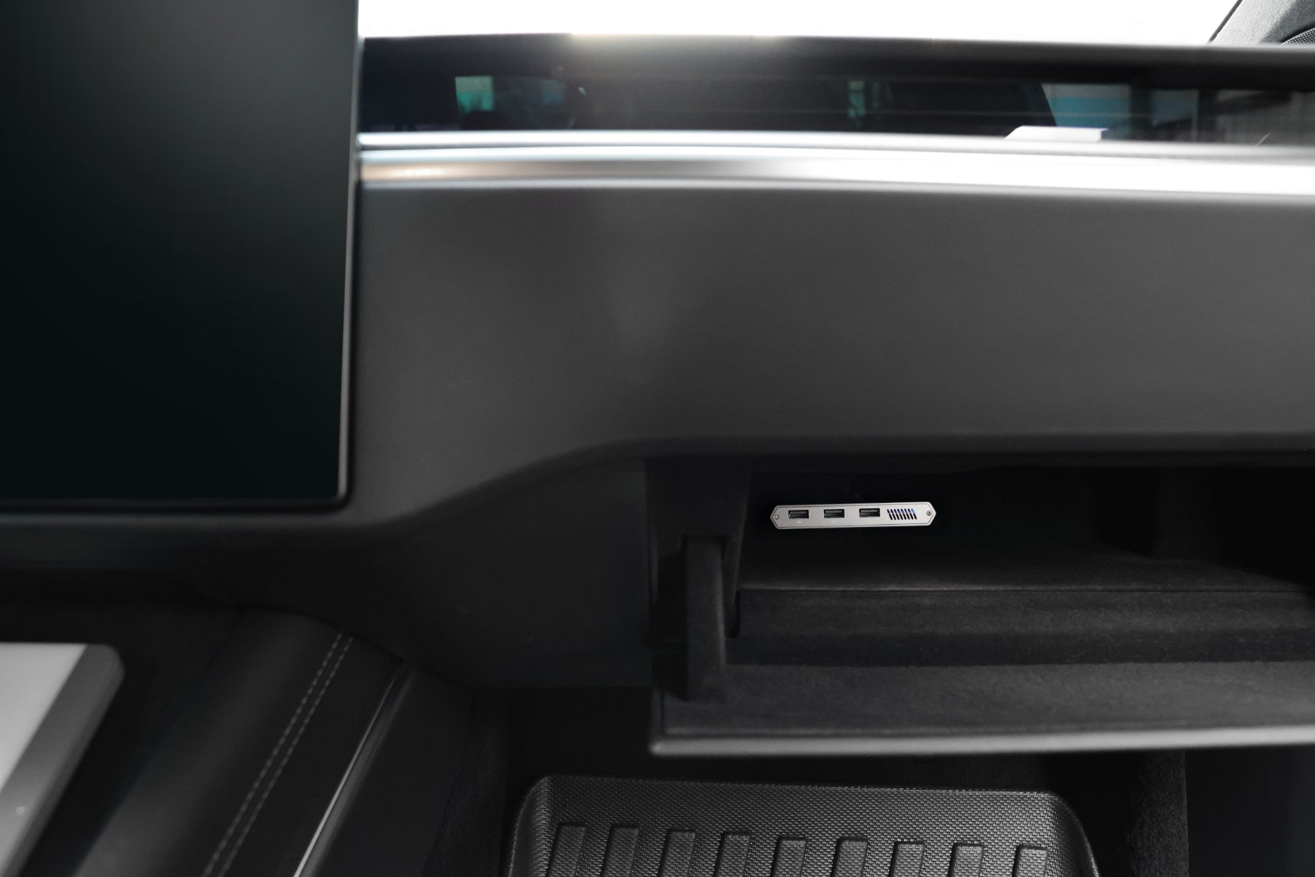 Close-up of a Tesla dashboard with an open glove compartment showing the JOWUA Tesla 1TB SSD + 3-Port HUB, ideal for Sentry Mode storage or connecting multiple devices. Part of the display and car interior are also visible.