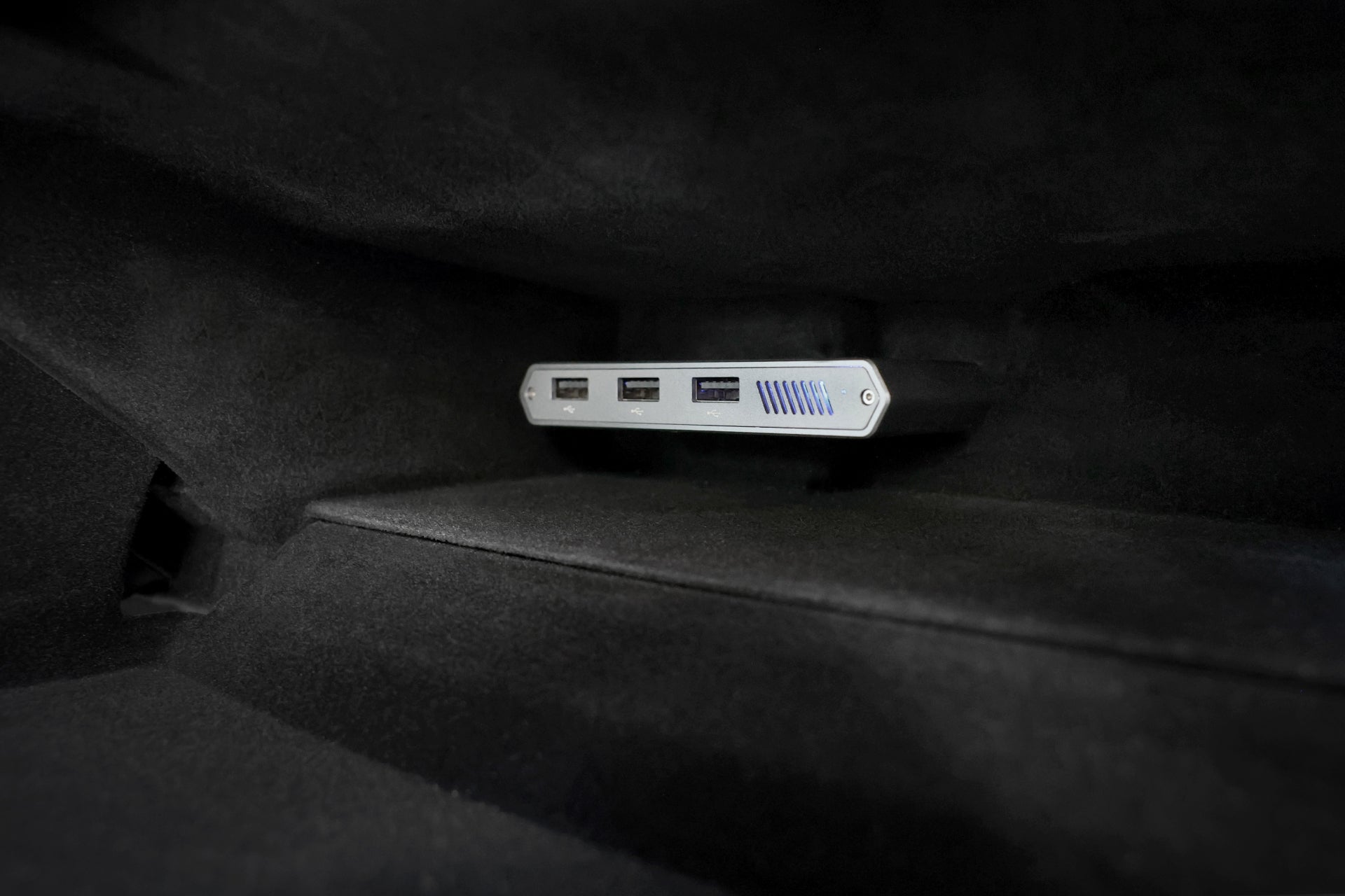 A close-up of the JOWUA Tesla 1TB SSD + 3-Port HUB, ideal for Sentry Mode storage, mounted inside a dark carpeted compartment.