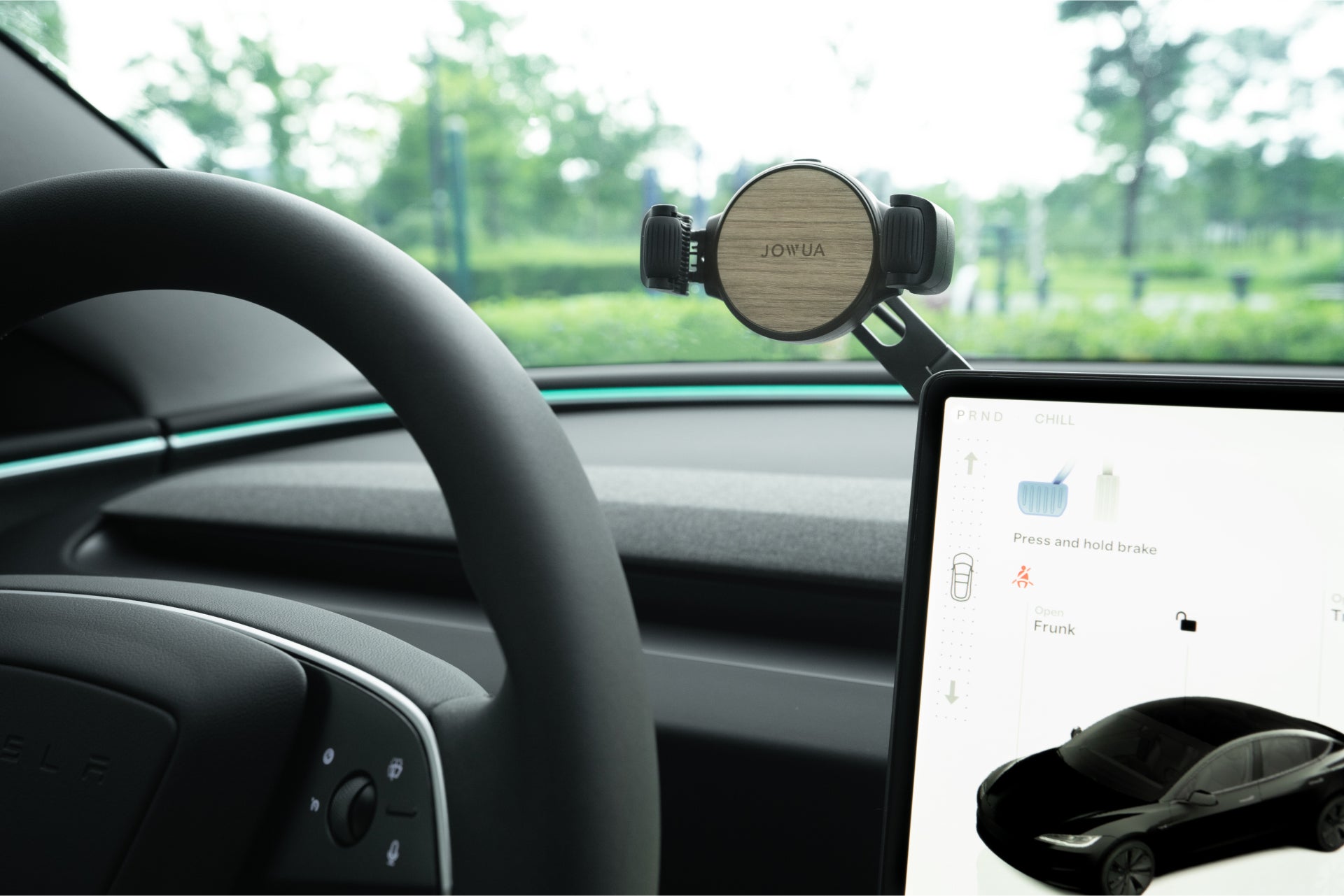 A Tesla driver's seat features a JOWUA 6D Tesla Compatible Invisible Foldaway Car Mount Qi2 Wireless Charger securely holding a phone.