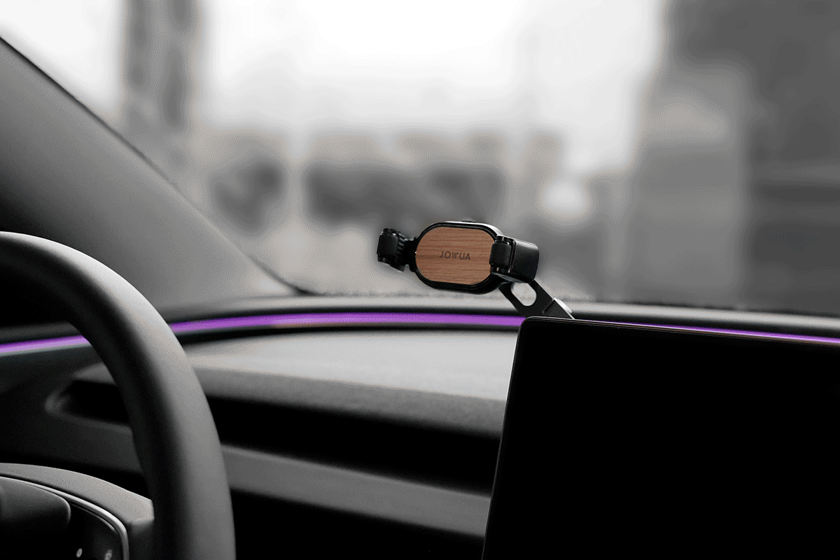 The JOWUA 6D Invisible Foldaway Car Mount, featuring a sturdy wooden back and adjustable angles for optimal viewing, enhances your dashboard. It boasts sleek lines with subtle purple ambient lighting, while the steering wheel and part of the windshield remain visible.