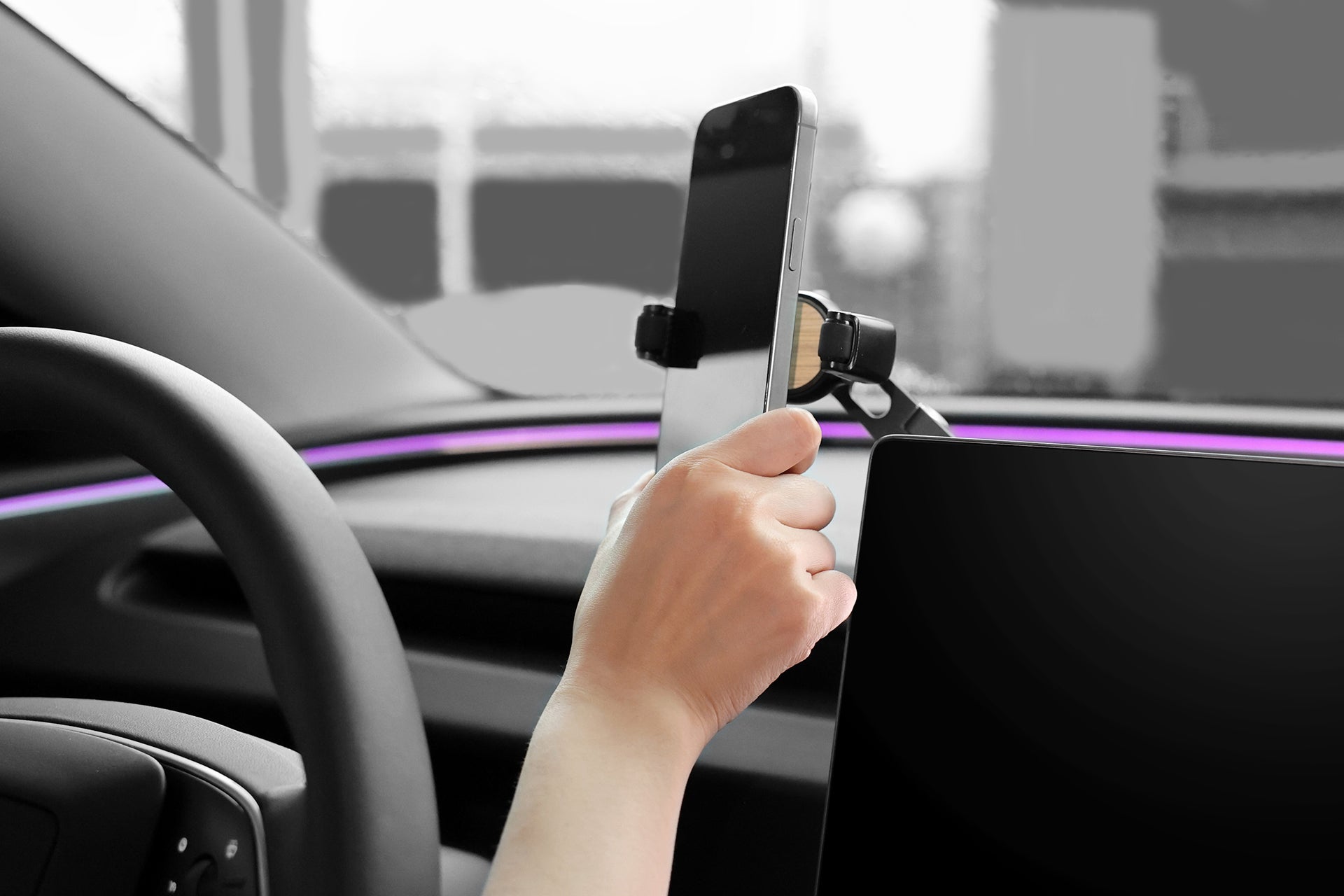 A person arranges a JOWUA 6D Invisible Foldaway Car Mount (Universal) on a dashboard, with the sleek interior's digital display enhancing the mount's adjustable angles. The blurred modern vehicle interior adds to the innovative ambiance.