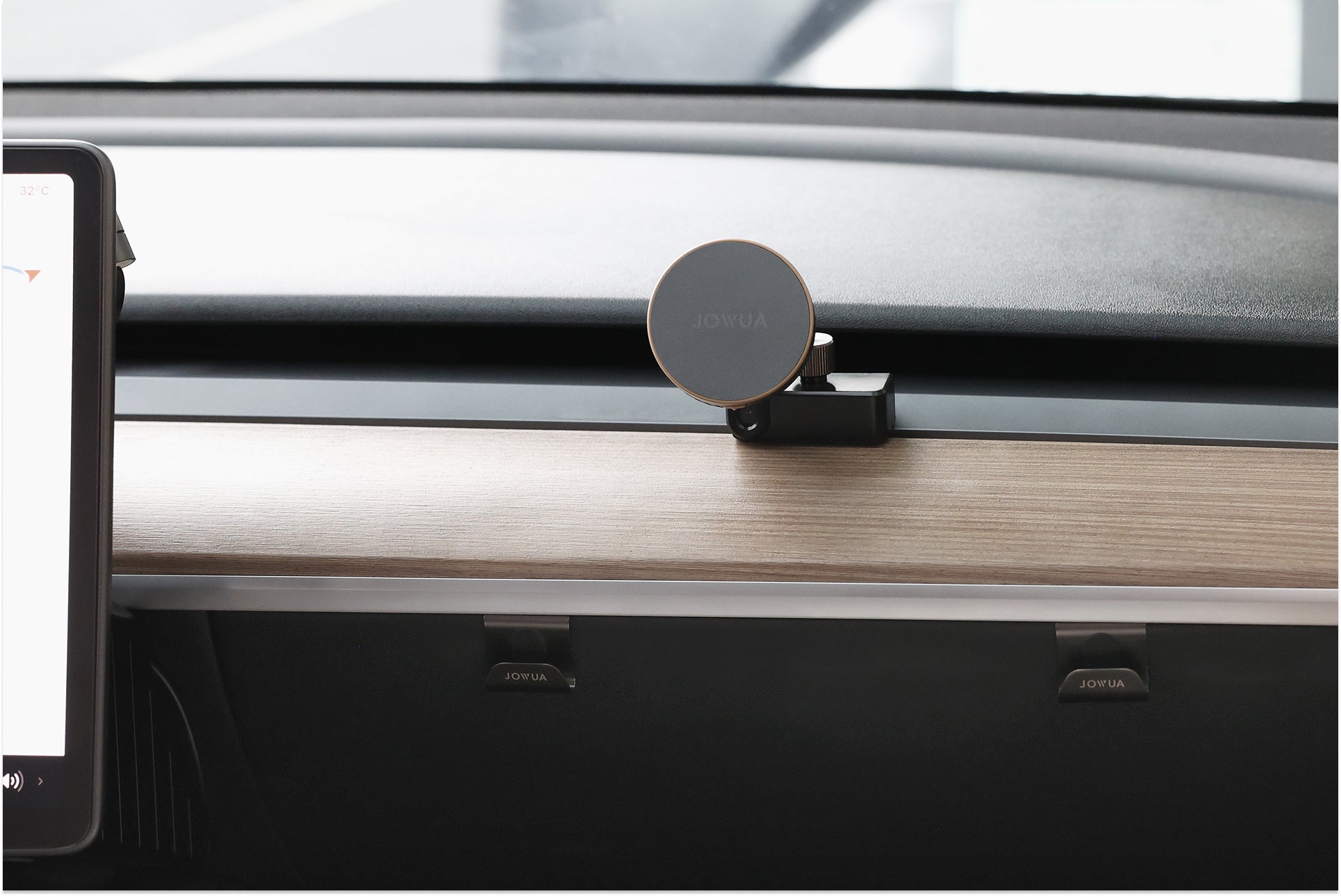 A minimalist car dashboard features a JOWUA Active Cooling MagSafe Car Mount for Air Vents (Model 3/Y 2018-2024), positioned above a wood-grain panel, with part of a digital display visible on the left side.