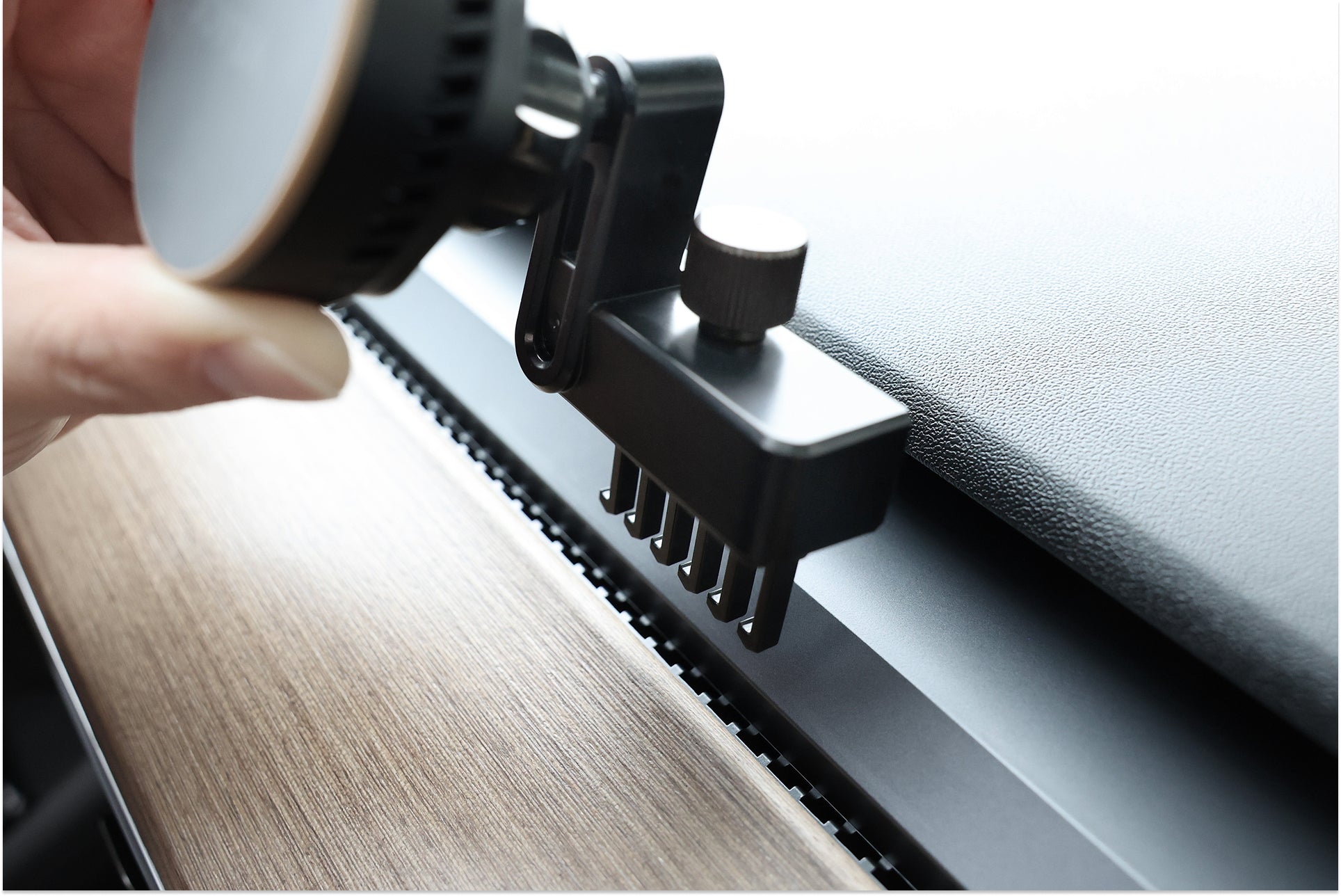A hand adjusts the JOWUA Active Cooling MagSafe Car Mount for Air Vents (Model 3/Y 2018-2024), which securely clamps to car vents using a knob and forked teeth—ideal for holding your MagSafe-compatible devices in place.