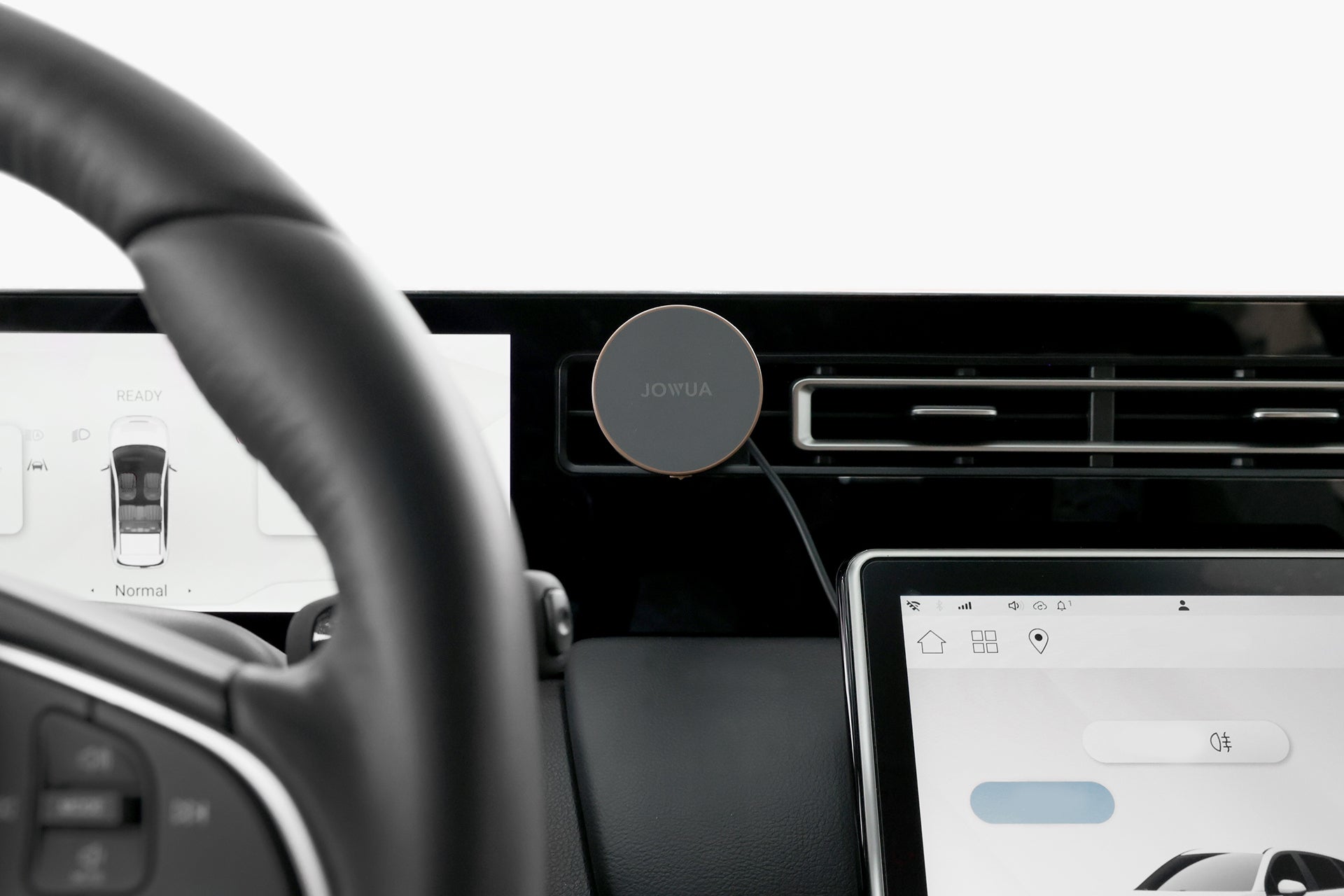 Close-up of a car dashboard featuring a steering wheel, touchscreen display with vehicle settings, and a JOWUA Active Cooling Universal MagSafe Car Mount for Air Vents attached to the air vent.