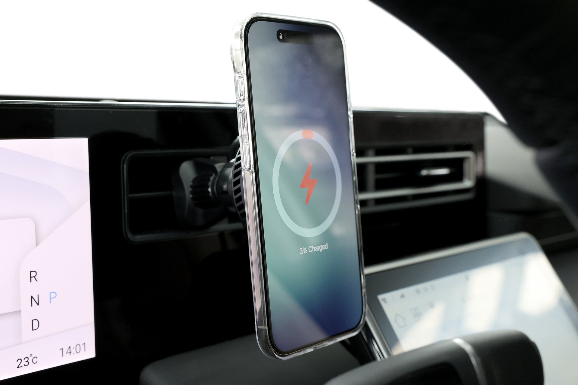 A JOWUA Active Cooling Universal MagSafe Car Mount for Air Vents holds a smartphone on the dashboard, displaying a 3% charging screen, with car controls and a digital climate/time display nearby.