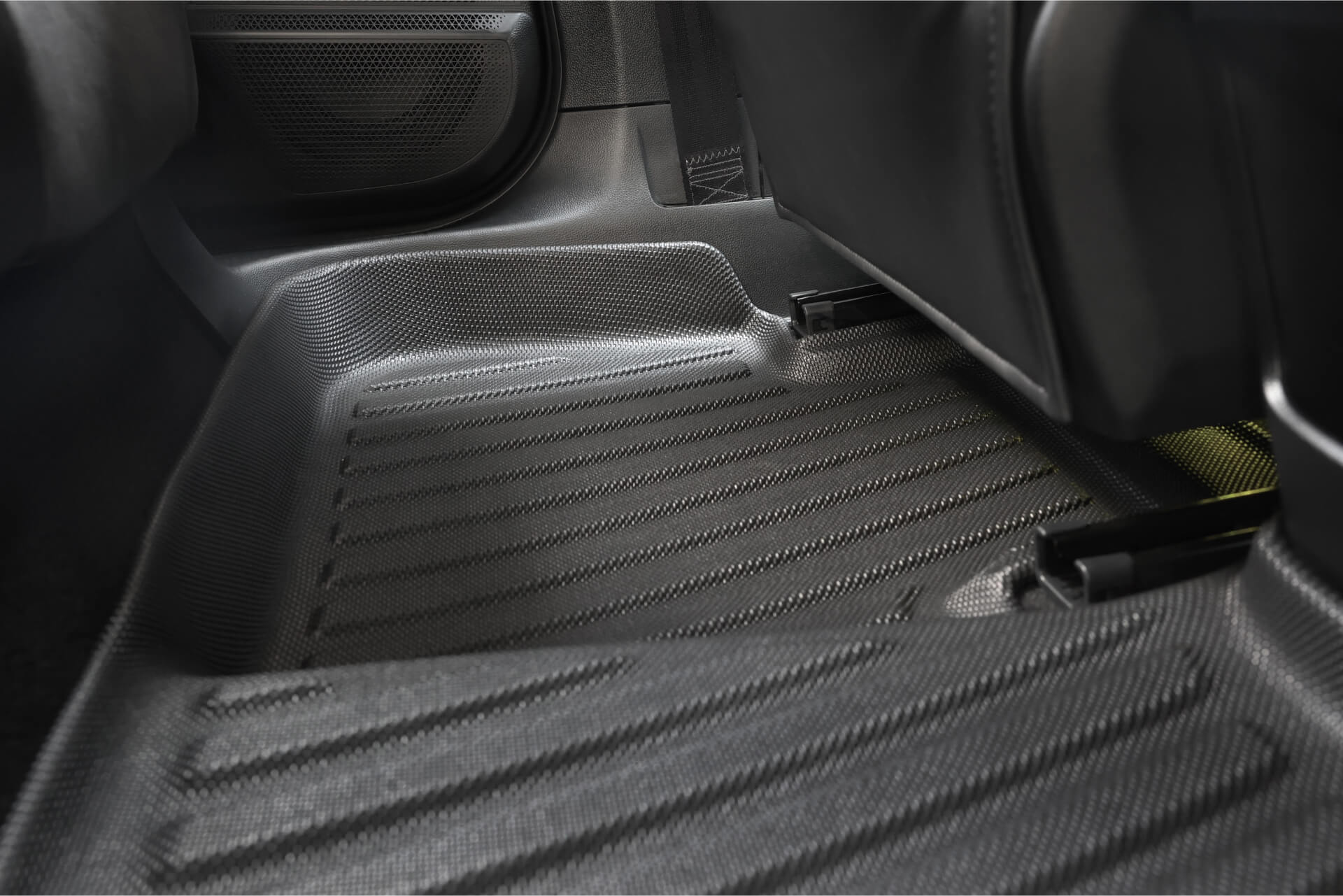 Close-up of the JOWUA All Weather Floor Liner (MG MG4) with a textured, ribbed surface installed in the rear footwell area, showing parts of the seats and door.