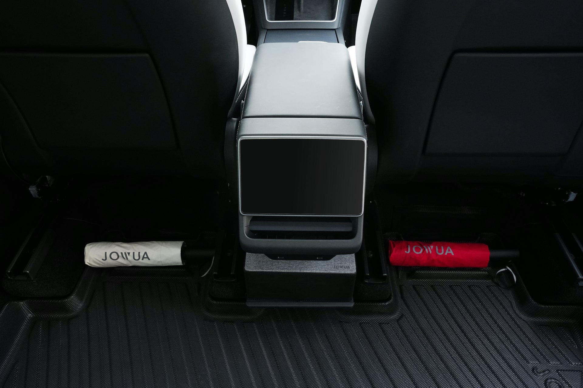A view of the Tesla Model Y backseat showcases the JOWUA Model Y (Juniper 2025+) All-Weather Floor Liners Combo, with a white and a red umbrella stored under each side of the center console.