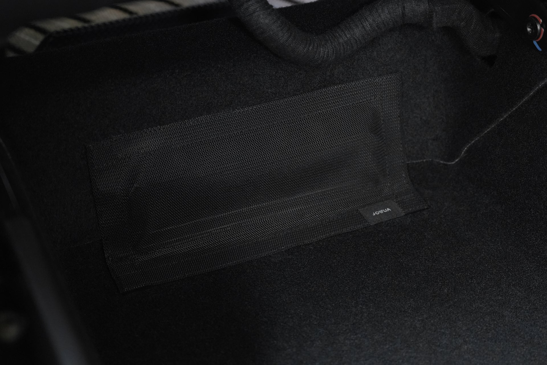 A close-up of a black mesh pocket labeled "HONDA" attached to the dark carpeted floor of a vehicle interior, much like how a JOWUA Tissue Box Holder fits seamlessly on Model Y (Juniper 2025+) All-Weather Floor Liners Combo.
