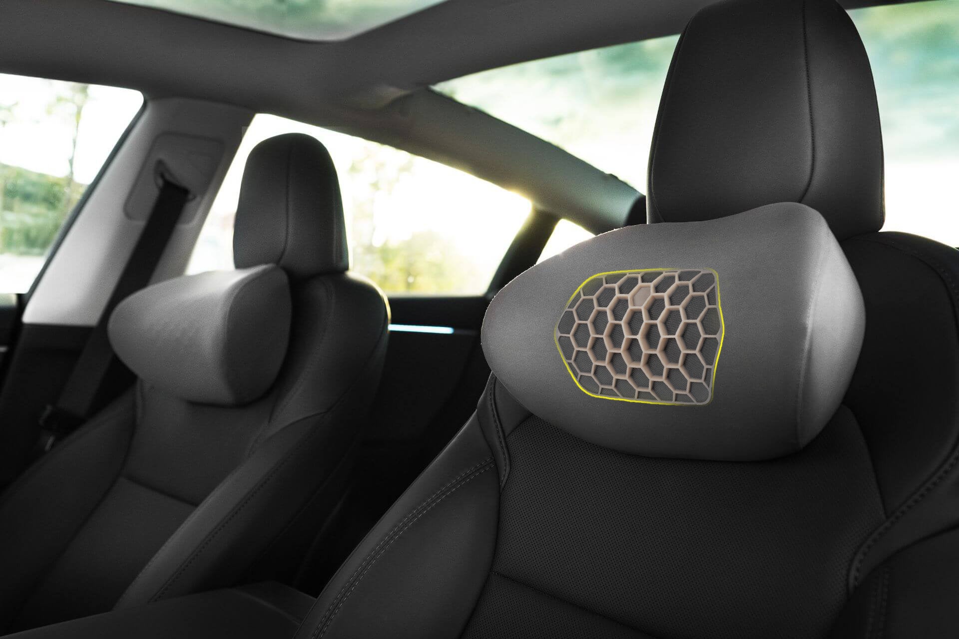 Close-up of the JOWUA Tesla Neck Pillow, featuring a hexagonal-patterned memory foam cushion attached to the front seat headrest for ergonomic neck support. The car interior looks clean and minimalistic.