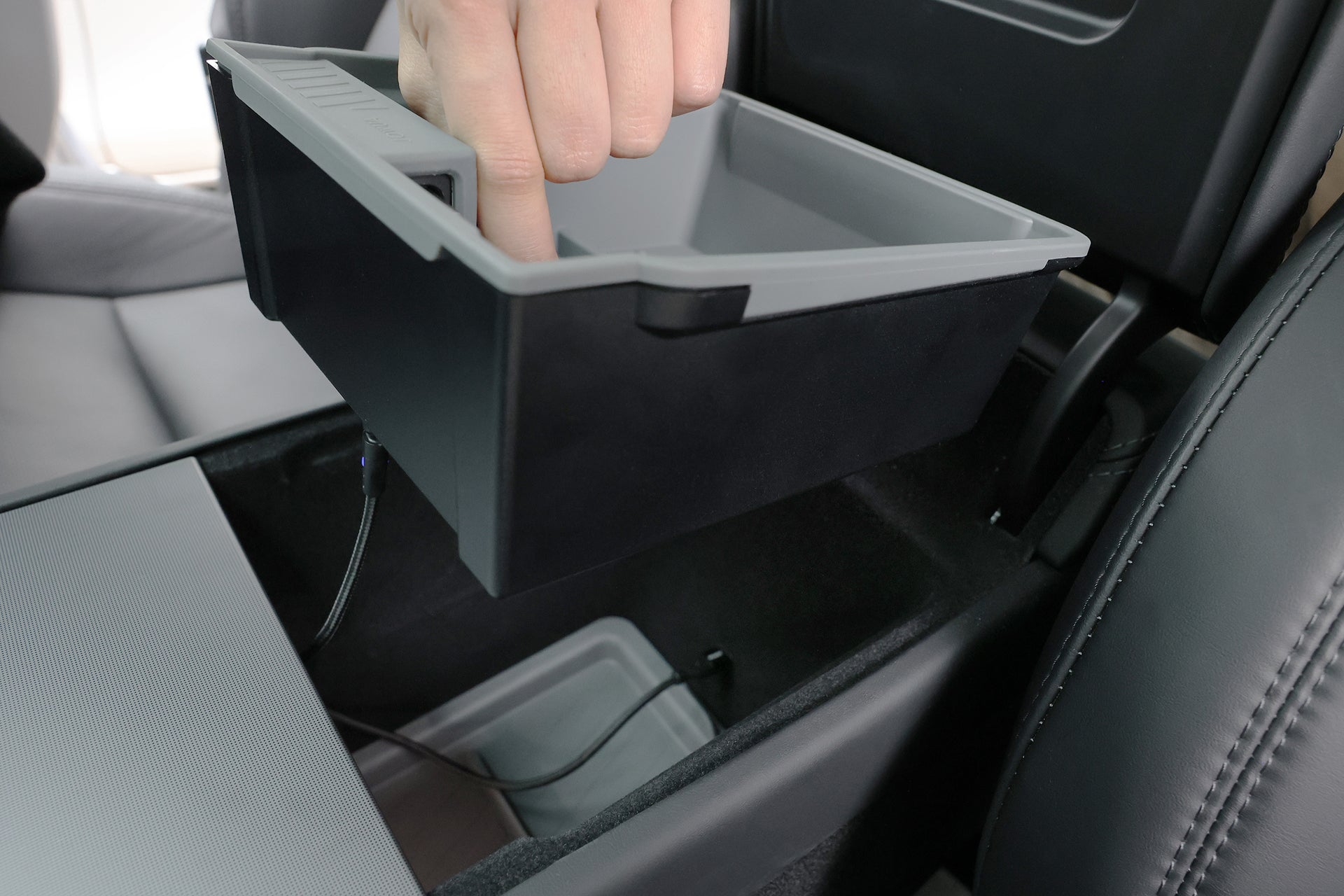 A hand lifts the removable tray with silicone mat from the JOWUA Center Console Organizer Set with Power HUB for Tesla Model 3 (2024-2026+) in a car's black interior.