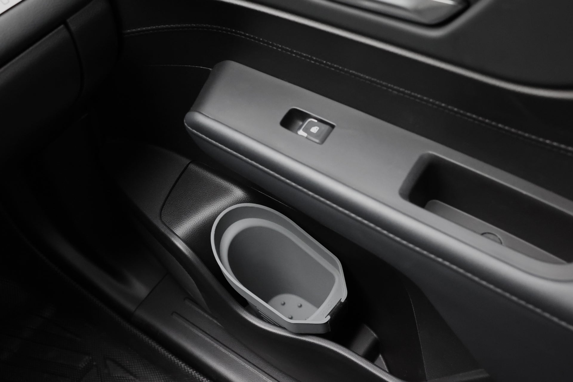 Close-up of a car’s interior door panel showing the JOWUA Door Side Storage Box (Set of 2) along with a window control button and an integrated grey cup holder.