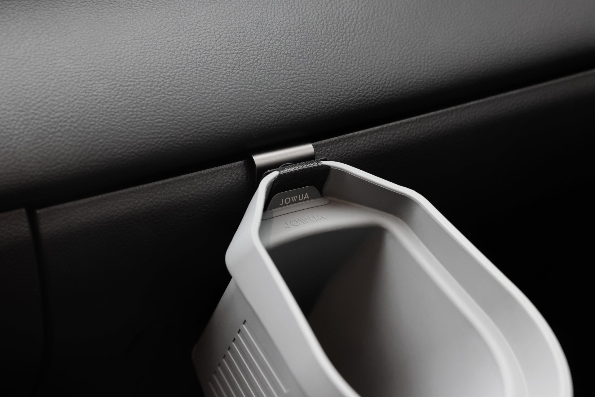 A close-up of a gray plastic Door Side Storage Box (Set of 2) by JOWUA, used as a car organizer and attached to the side of a black car interior panel.
