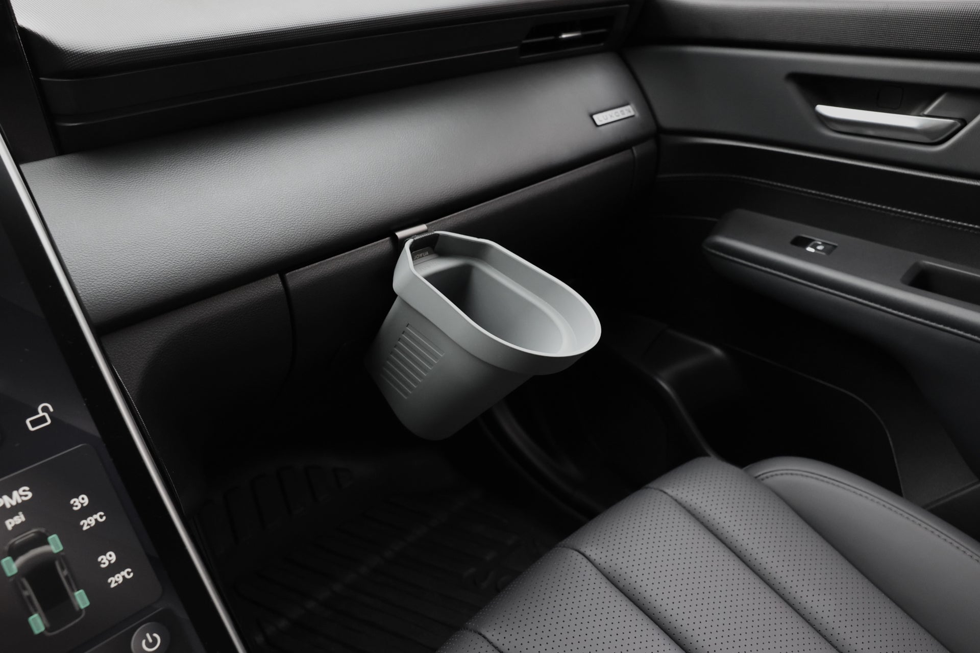 A close-up view of a car’s front passenger side interior with a JOWUA Door Side Storage Box (Set of 2) attached to the dashboard, positioned above a floor mat and next to the center console.