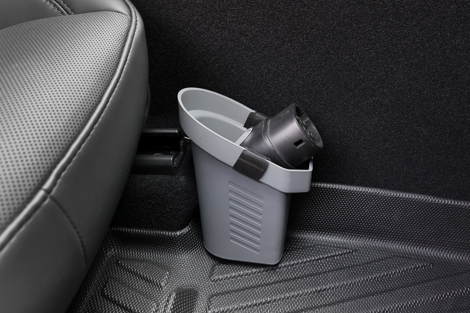 The JOWUA Door Side Storage Box (Set of 2) is a compact gray silicone organizer with a black lid, designed to attach to the back of a car seat and fit neatly on the floor mat near the seat's edge.