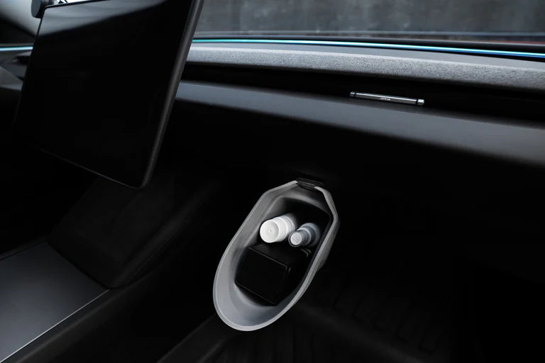 A close-up of a car’s interior shows the JOWUA Door Side Storage Box (Set of 2) neatly holding two small bottles and a black rectangular object, placed below the dashboard with a tablet-style screen above it.