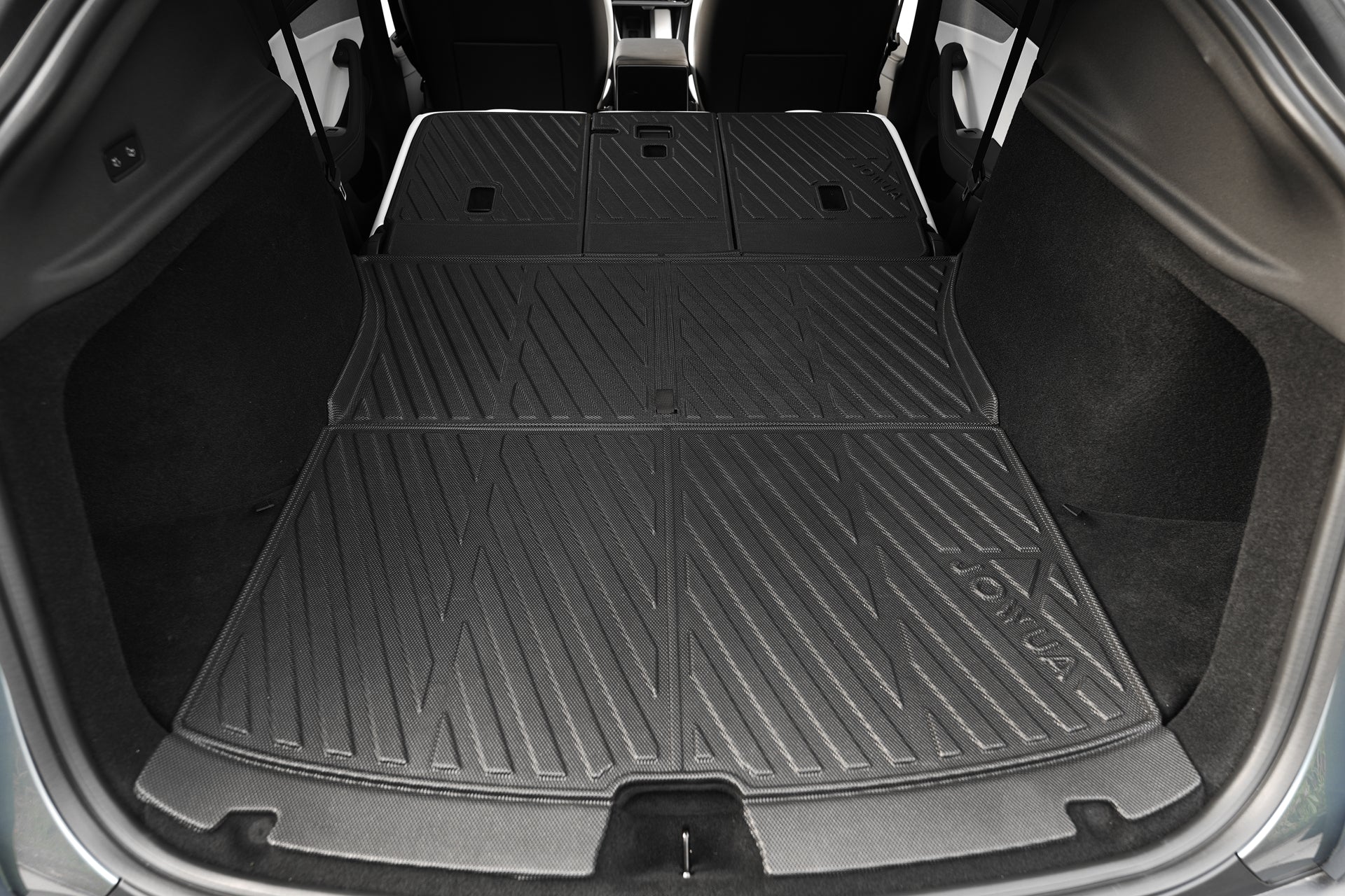 View of the cargo area of a Tesla Model Y (Juniper 2025+) with rear seats folded, protected by the JOWUA Model Y EasyShield Waterproof Trunk Liner + Rear Seats Back Cover Bundle featuring textured black TPE material.