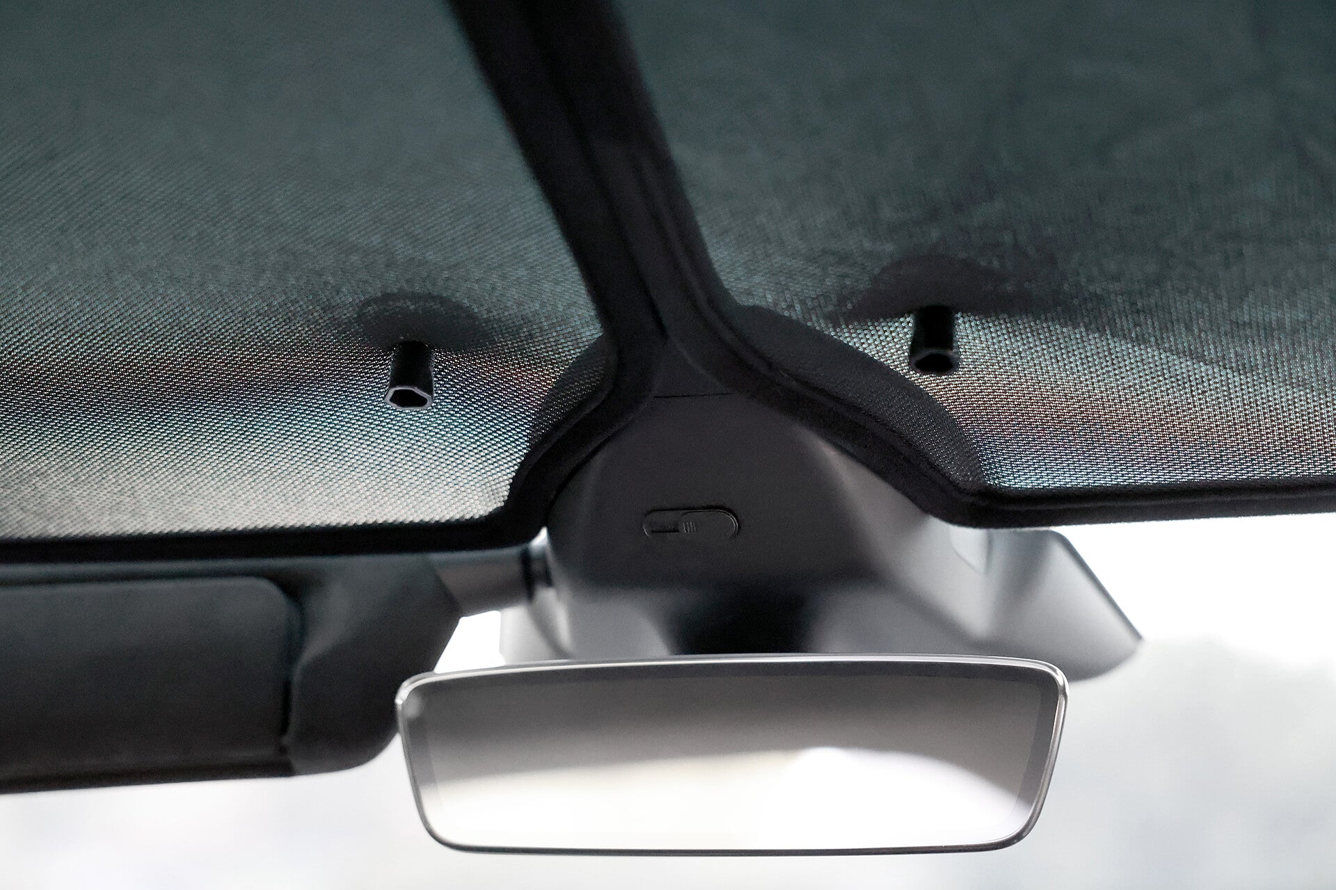 An interior view of a car roof with the JOWUA Glass Roof Sunshade- Separate Design (Model X) features a central black camera between textured fabrics, adding elegance and enhancing heat insulation. A rearview mirror is visible just below the setup.