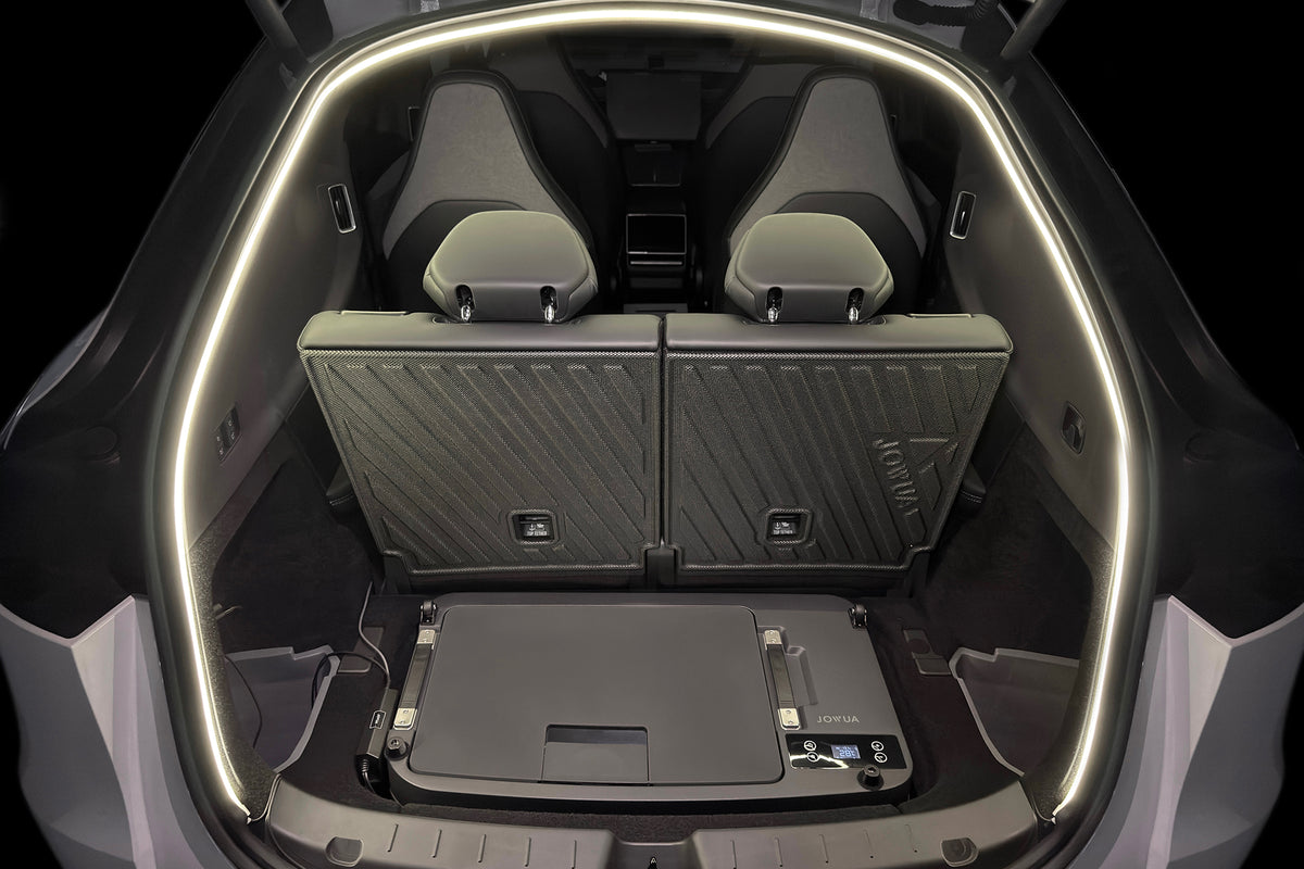 A slim, rectangular JOWUA Car Refrigerator for Tesla Model Y L (2026+) with intelligent dual-mode cooling sits on the floor of a vehicle’s cargo area behind the rear passenger seats.