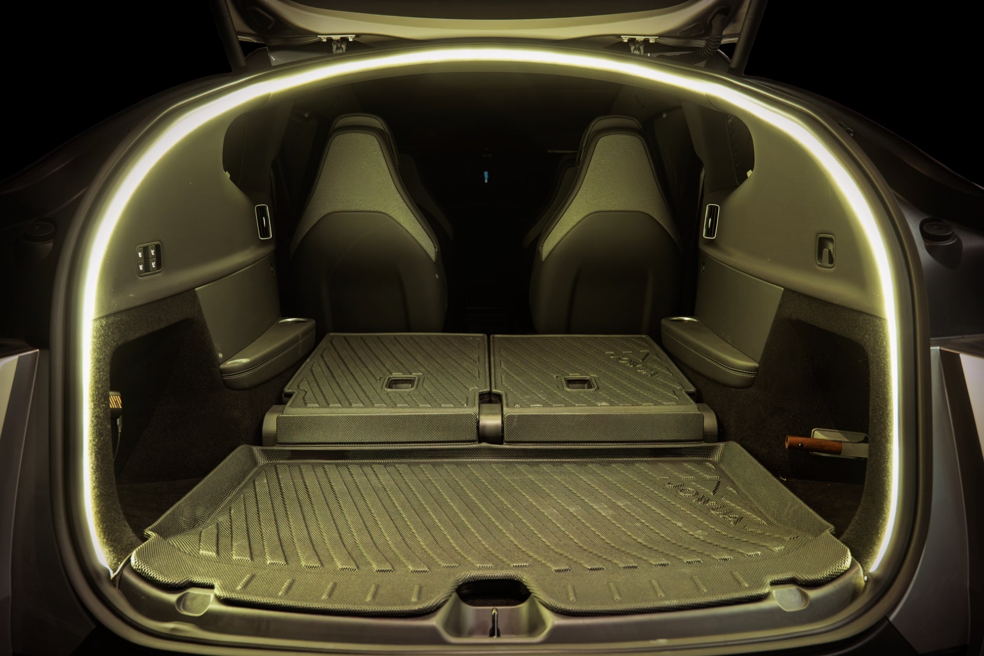 The image displays the open trunk of a Tesla Model Y L (2026+) with the rear seats folded flat, revealing an expansive cargo area. Within this space, JOWUA Trunk Storage Bins are neatly arranged to enhance organization and maximize storage options. The trunk is illuminated by ambient lighting from the JOWUA Ambient Light Bundle outlining the opening for improved visibility.