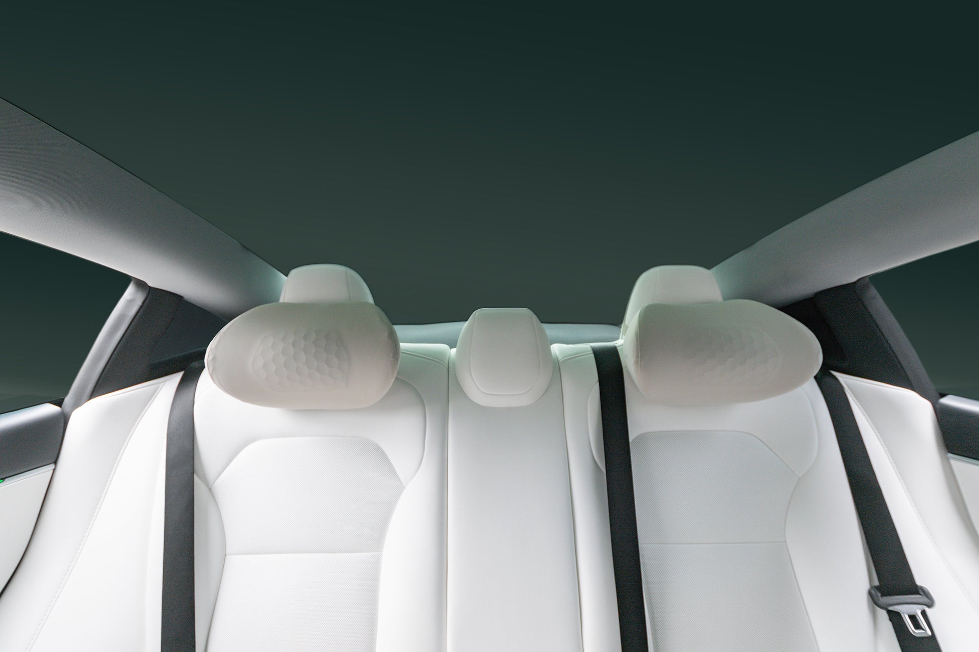 Interior rear view featuring three white seats, two ergonomically designed JOWUA Tesla Neck Pillow headrests, and two seat belts against a dark background, photographed from inside the vehicle.