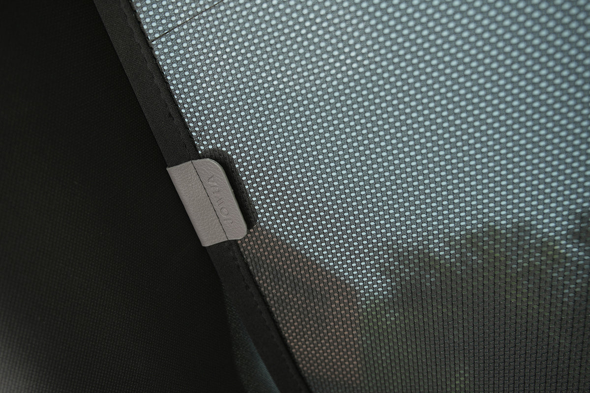 Close-up of a mesh fabric screen from the JOWUA Rear Lift Gate + Triangular Window Sunshade for Model Y L (2026+), highlighting the fine texture and stitching details. The image showcases the precise craftsmanship characteristic of this custom-fit sunshade, with blurred greenery visible in the background through the mesh.