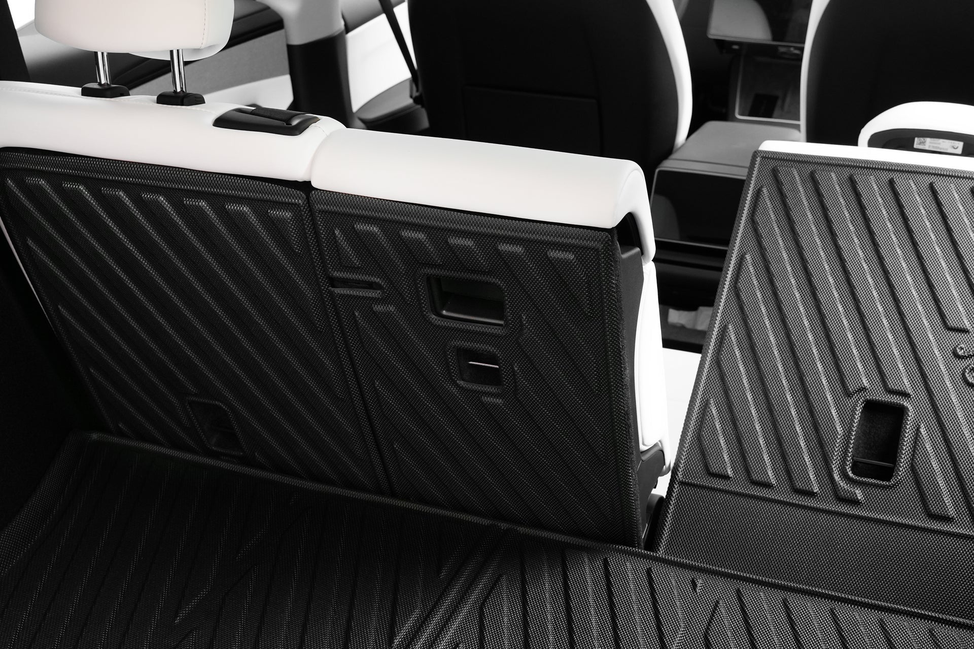 Close-up of the JOWUA Model Y (Juniper 2025+) EasyShield Waterproof Trunk Liner + Rear Seats Back Cover Bundle, showcasing partially folded rear seats and flexible cargo space with black and white upholstery and textured panels.