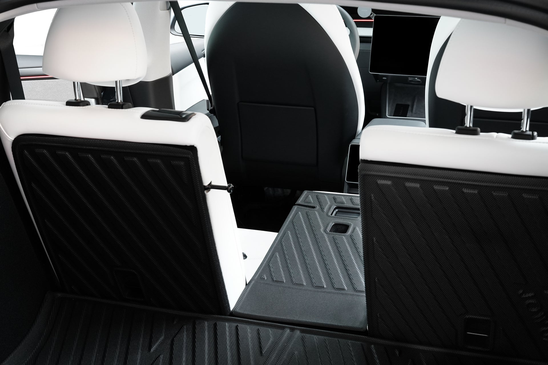 Rear view of a Tesla Model Y (Juniper 2025+) interior with back seats folded, showing extended cargo space protected by the JOWUA EasyShield Waterproof Trunk Liner + Rear Seats Back Cover Bundle. White seats contrast with rugged black TPE liner.