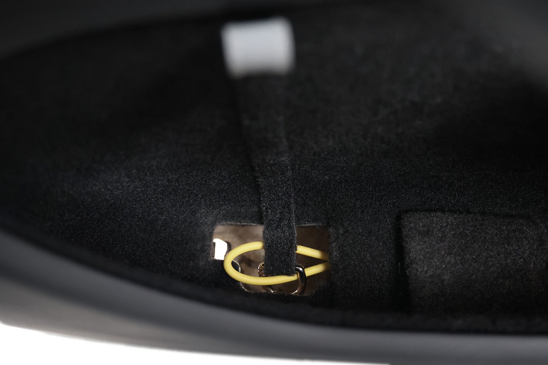 A gold key ring is attached to the JOWUA Reflective Rear Door Emergency Release Strap for Model 3 Highland (2024+) / all Model Y, shown inside a soft, fabric-lined black compartment with a partially shadowed interior.