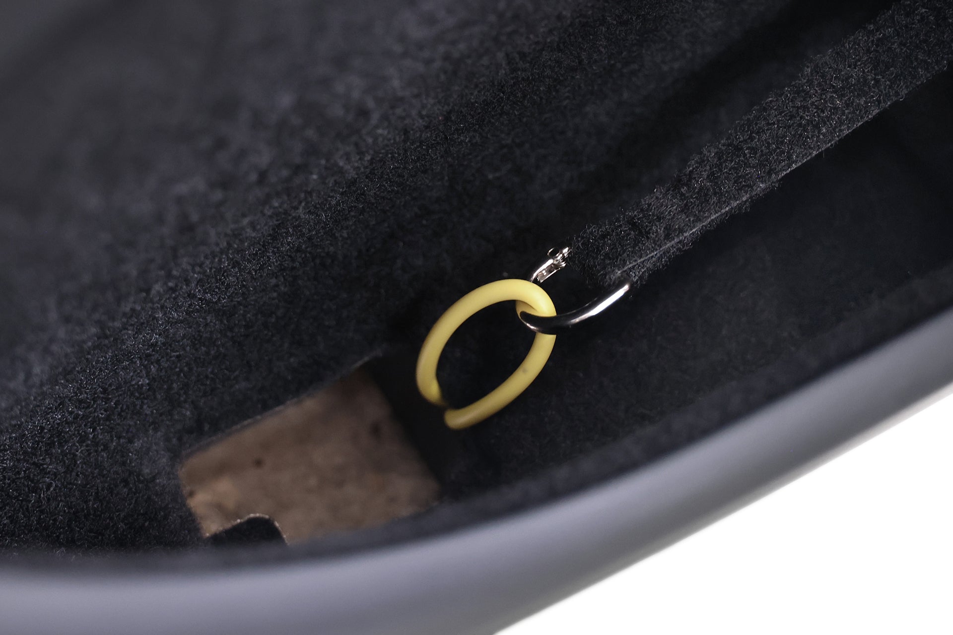 Close-up of the JOWUA Reflective Rear Door Emergency Release Strap (Model 3 Highland 2024+ / All Model Y), featuring a small keyring with a yellow plastic ring, attached inside a black bag lined with soft material for added visibility and thoughtful design.