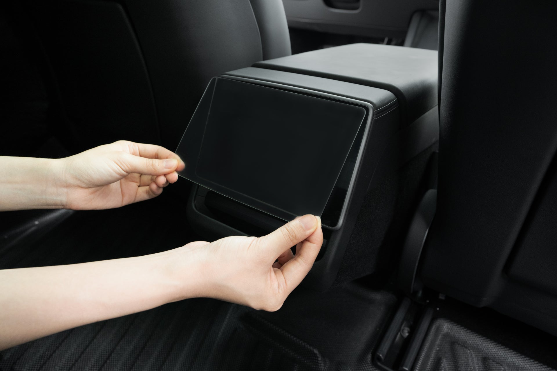 Hands gently install a large, transparent cover over the dashboard screen in the sleek Tesla Model Y Juniper (2025+) with JOWUA Premium Bundle, featuring wireless charging.
