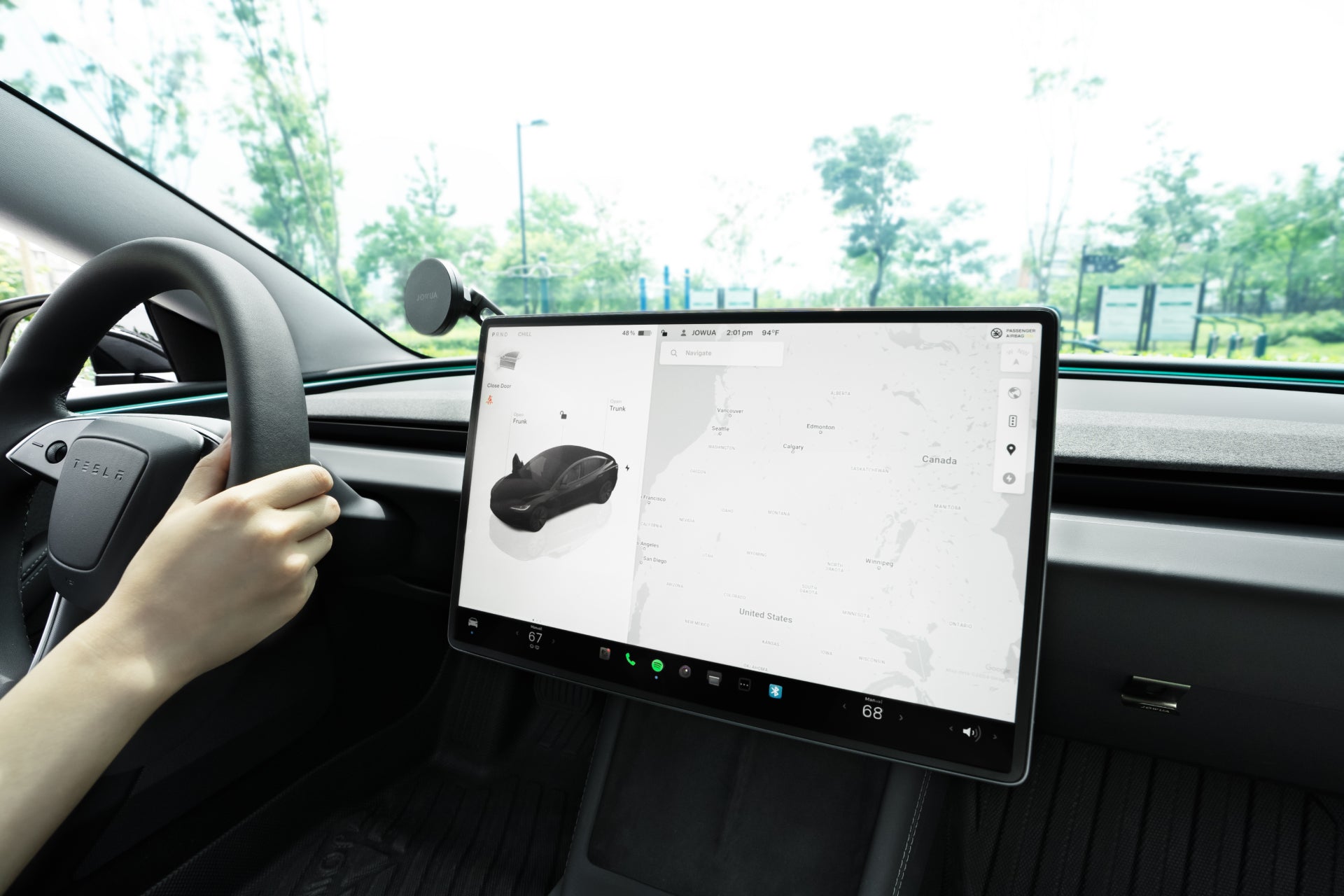 A person drives a Tesla Model 3 2024+ with a large touchscreen showing a map and digital whoopee cushion, protected by the JOWUA Tempered Glass Screen Protector 15" for Model Y 2025+/Model 3 2024+.