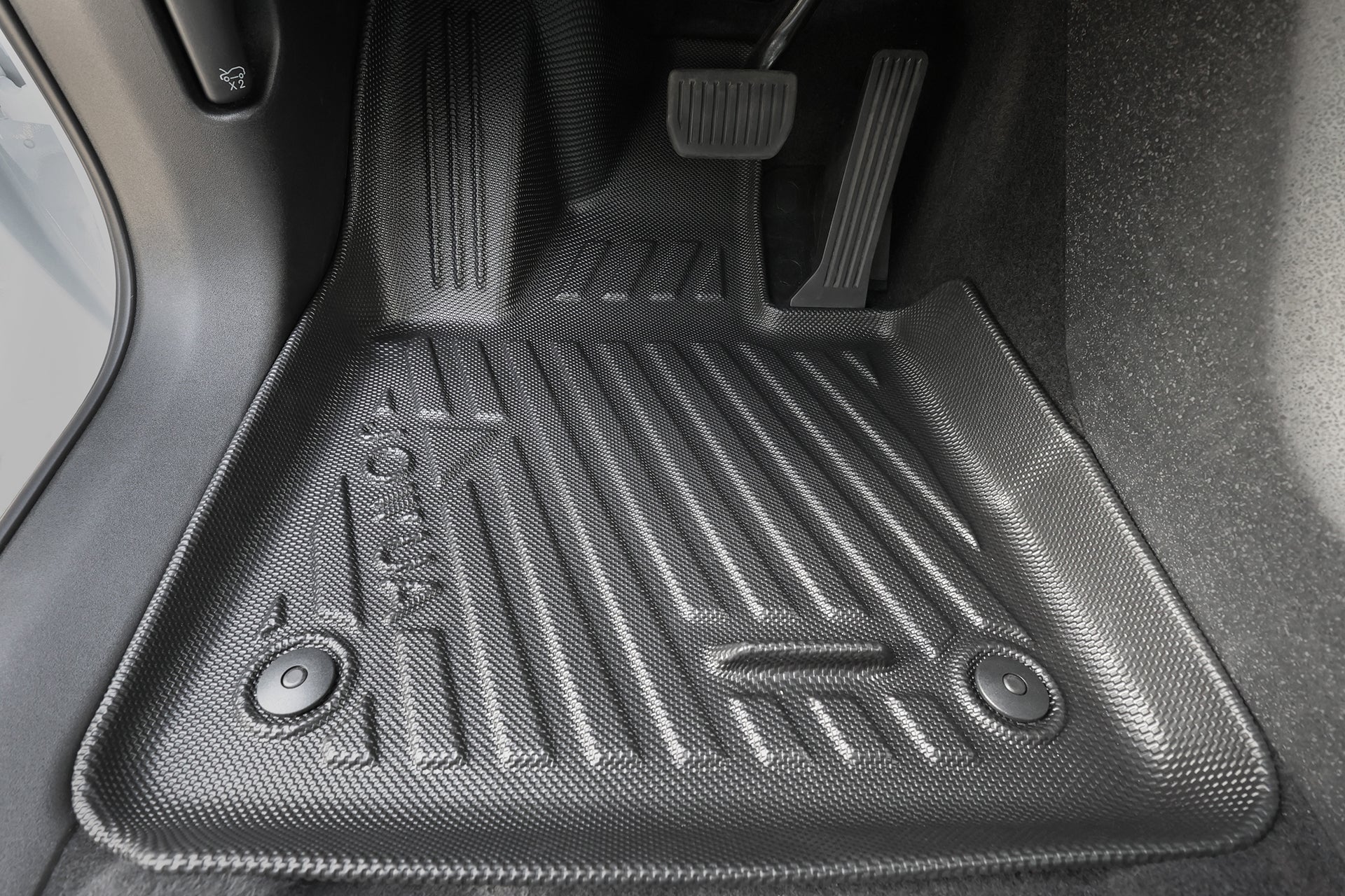 Close-up of the JOWUA All Weather Floor Liner (Volvo EX30) custom-fit in the driver’s footwell, highlighting two round fasteners and embossed patterns near the accelerator and brake pedals.
