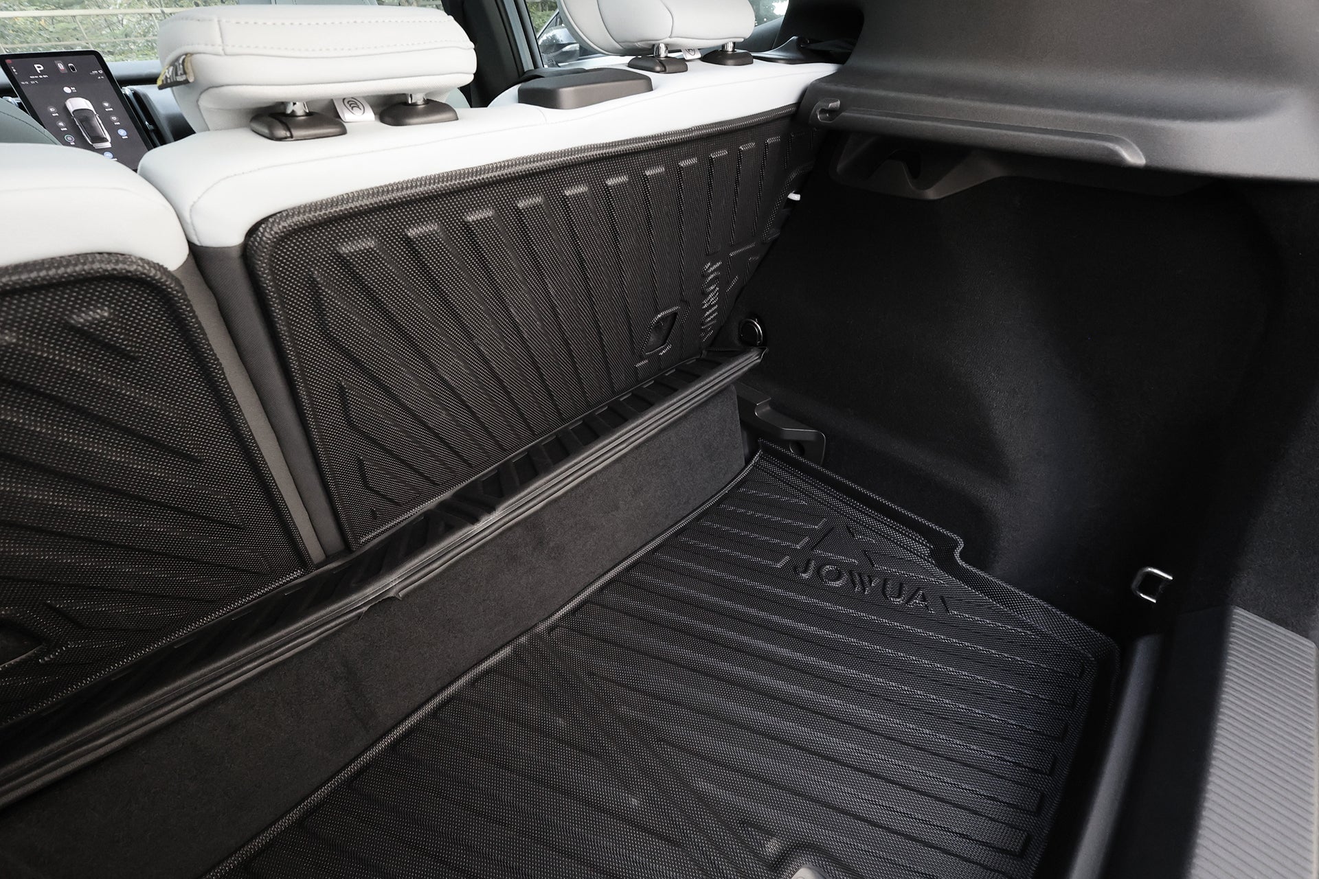 Close-up of a Volvo EX30’s rear cargo area with the JOWUA All Weather Trunk Liner and Rear Seat Cover, showing custom-fit protection and split-fold rear seatbacks in white and black, both folded up.