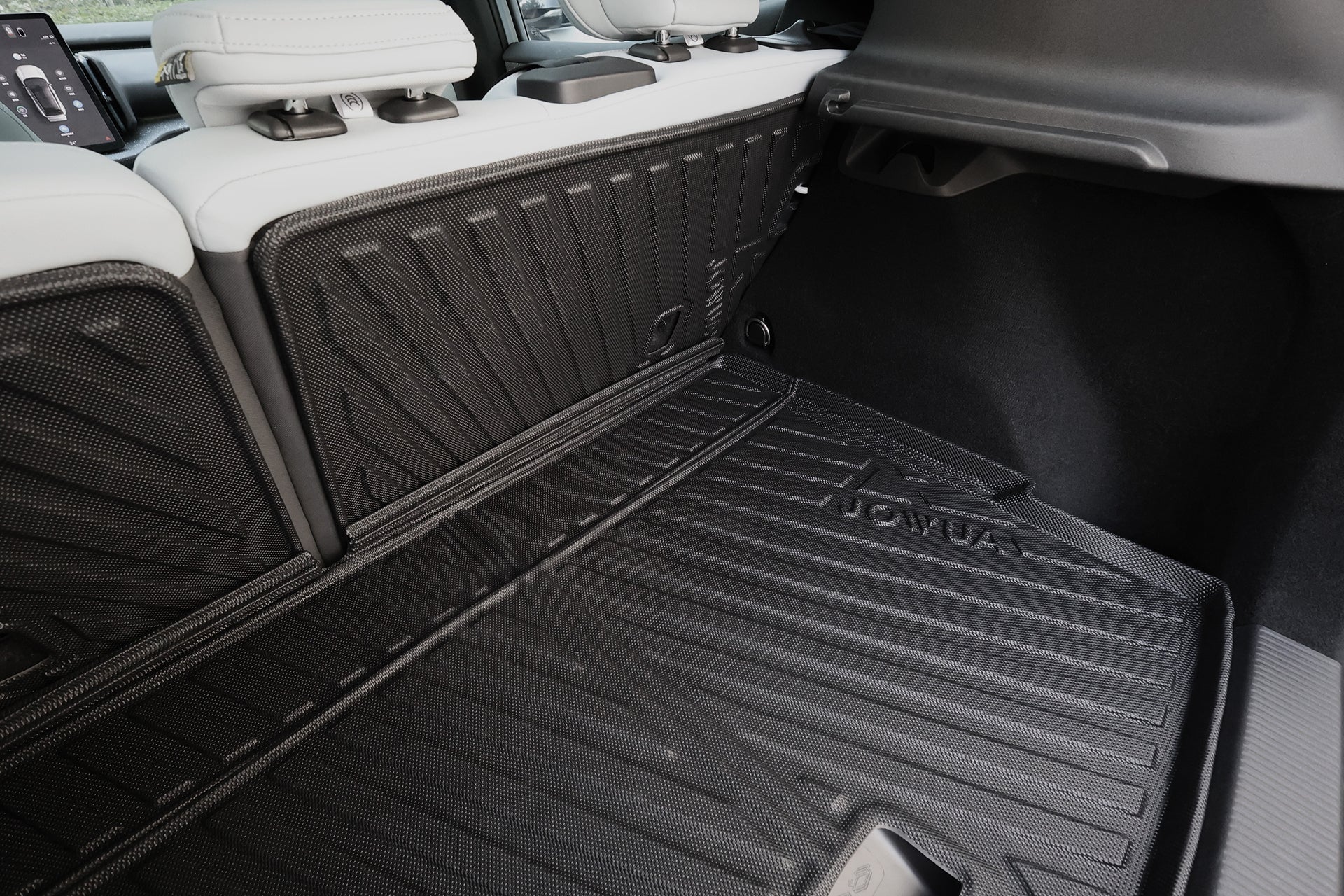 Close-up of a Volvo EX30 with JOWUA All Weather Trunk Liner + Rear Seat Cover. The custom-fit mat protects the trunk floor and rear seat backs, shown with white leather seats in the background.