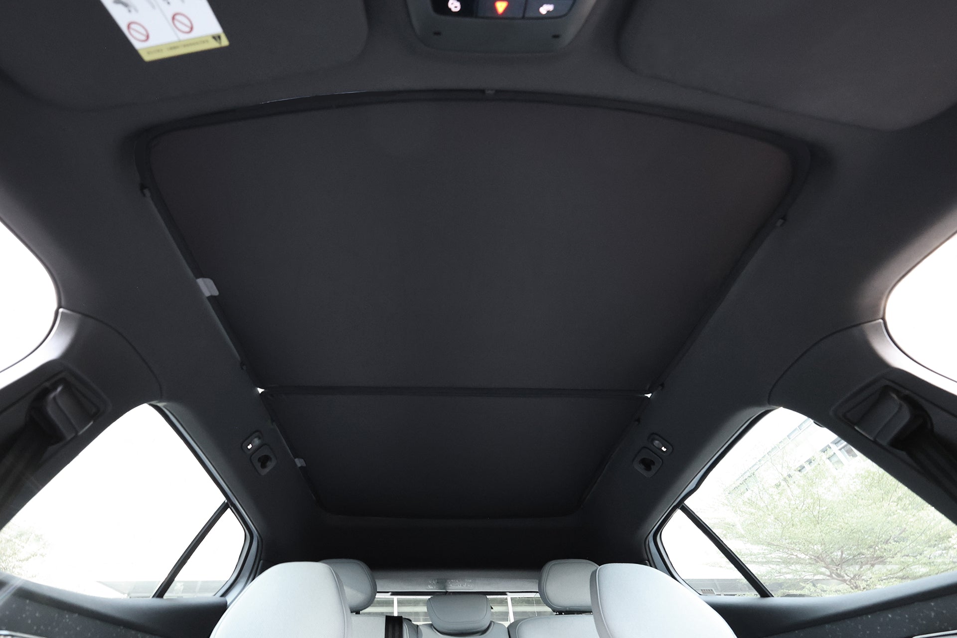 Enjoy the view from your Volvo EX30’s back seat with JOWUA's Glass Roof Sunshade—designed for UV protection while letting in natural light through the closed sunroof, complemented by light gray seats and large side windows.