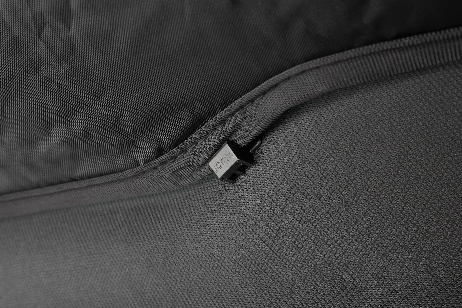 Close-up of a black zipper, partially open on textured fabric, as seen on the JOWUA Side + Rear Liftgate Window Sunshade for Model Y Juniper (2025+), showing the zipper pull and teeth in detail.