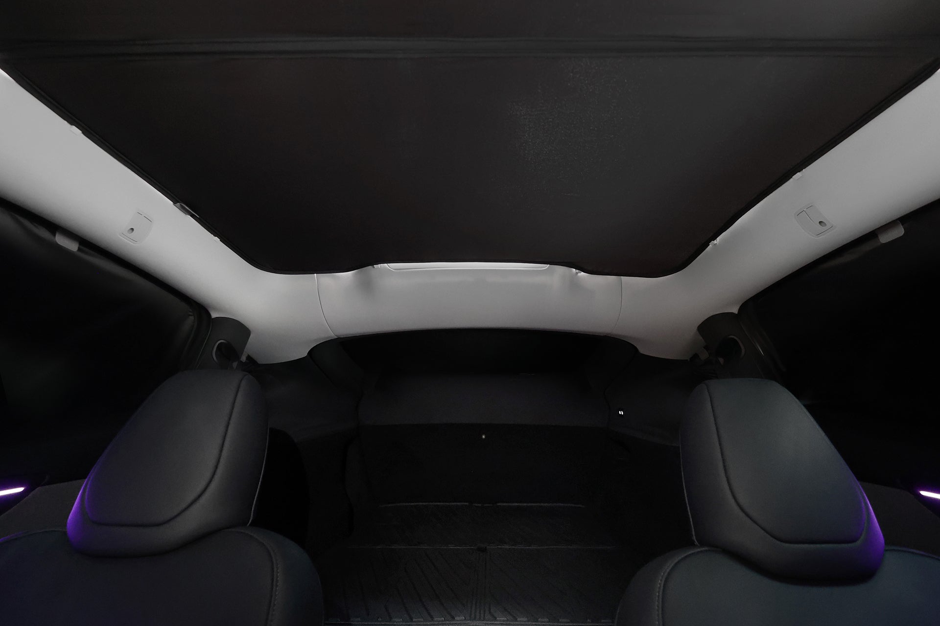 Interior view featuring two front seats, a black panoramic glass roof shaded with JOWUA’s Side + Rear Liftgate Window Sunshade for Model Y Juniper (2025+), and a spacious rear cargo area, all in a sleek, modern design.
