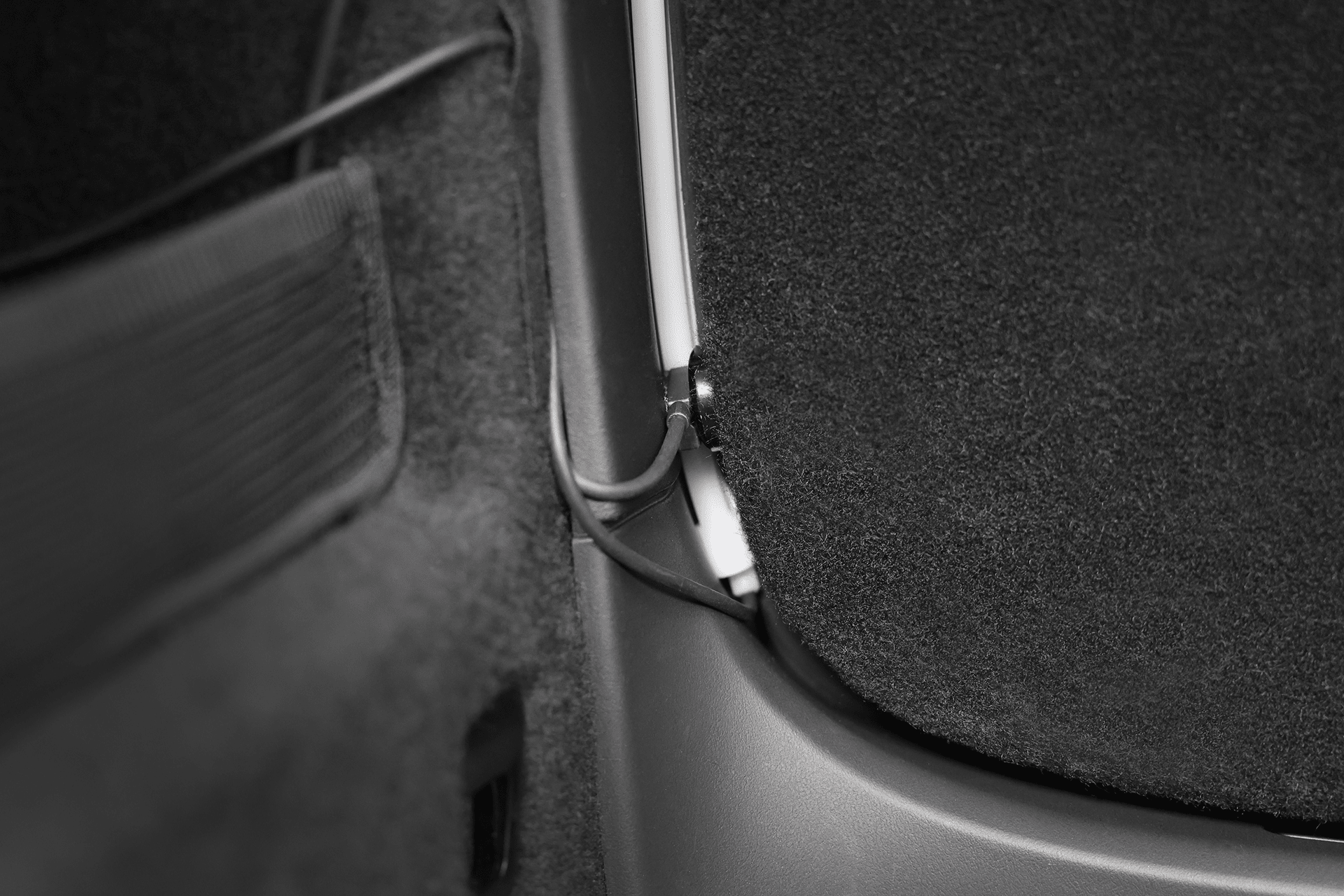 Close-up of a JOWUA Tesla Model X Trunk Ambient Light—USB-C LED Strip—shows a black cable along the side panel, partly tucked between fabric and plastic, with a mesh pocket on the left enhancing the trunk’s illuminated look.